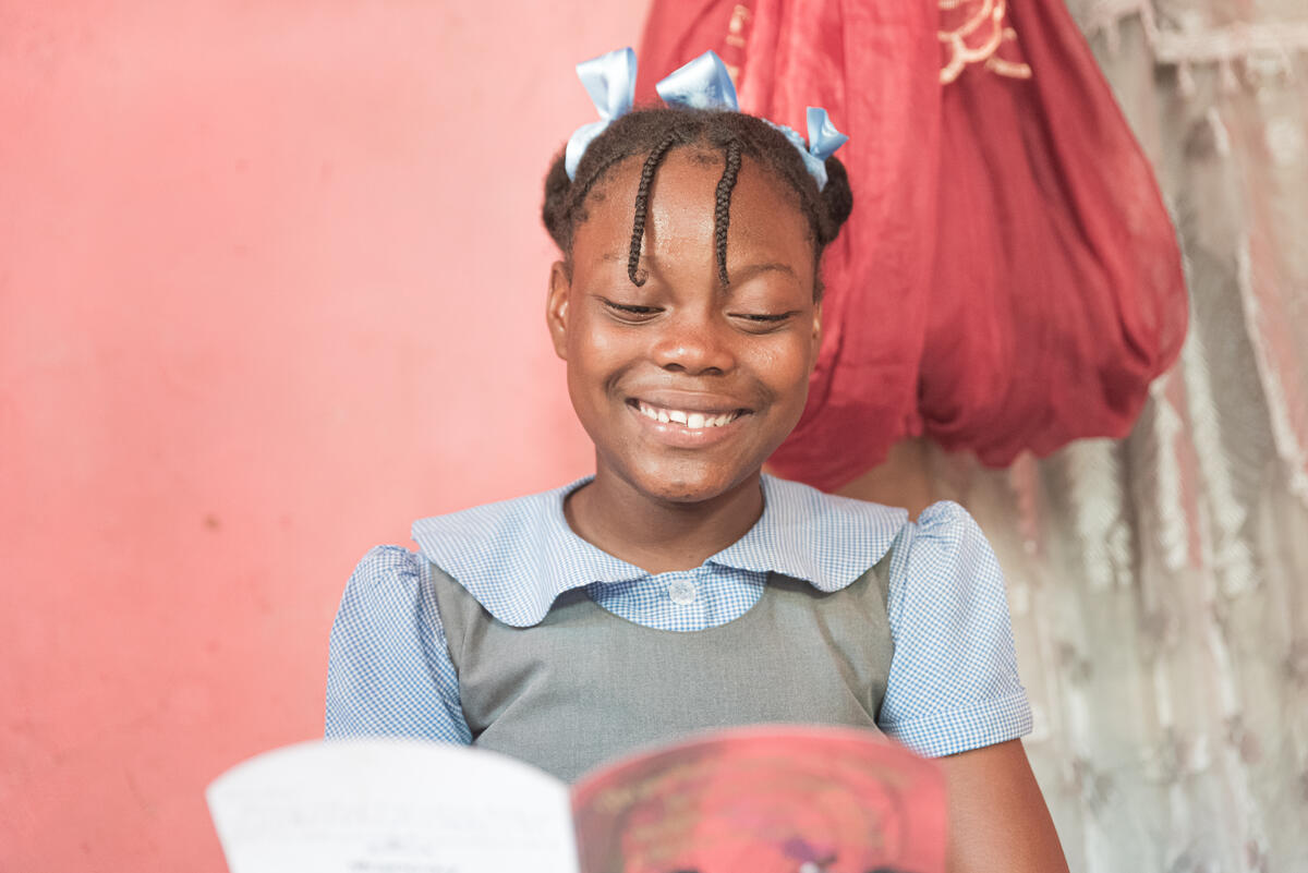Child in Haiti reads a letter from her sponsor and smiles