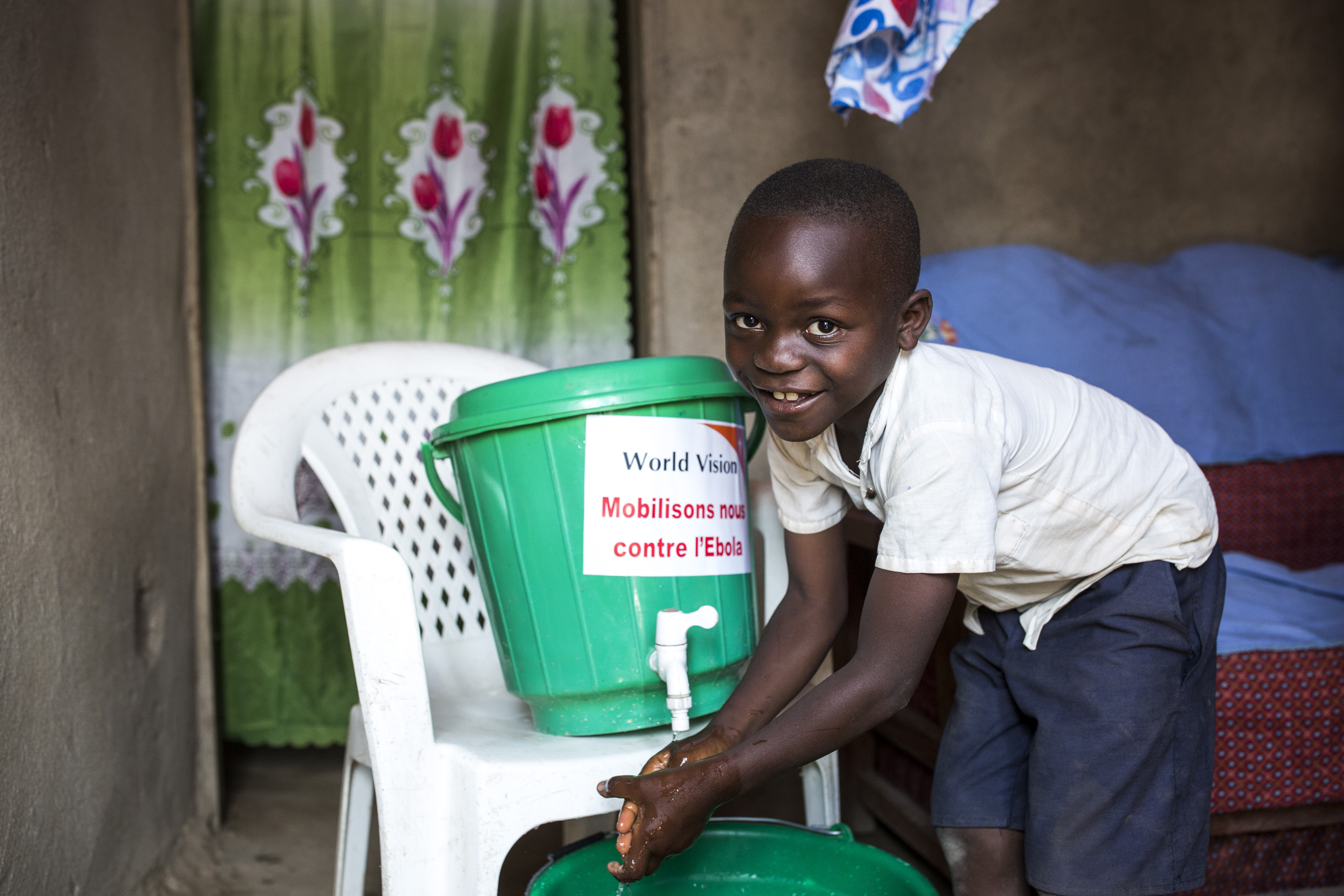 A young boy smiles while washing his hands at a World Vision water point