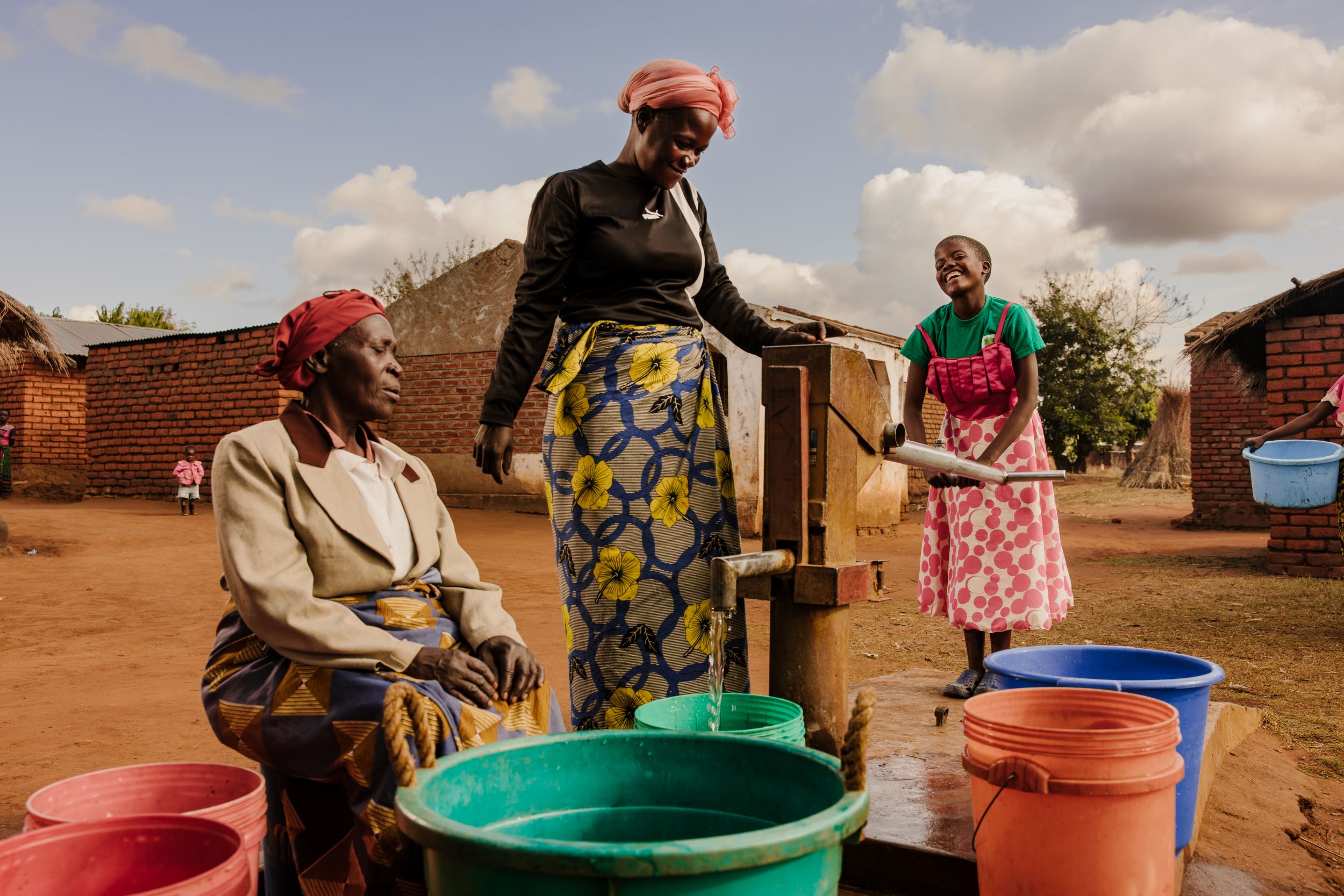 Three generations of Malawi women at a water pump