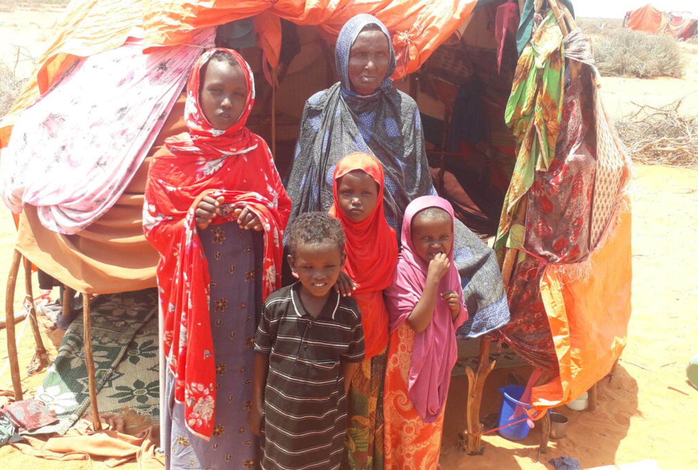 Somalian grandmother and four of her grandchildren outside their shelter