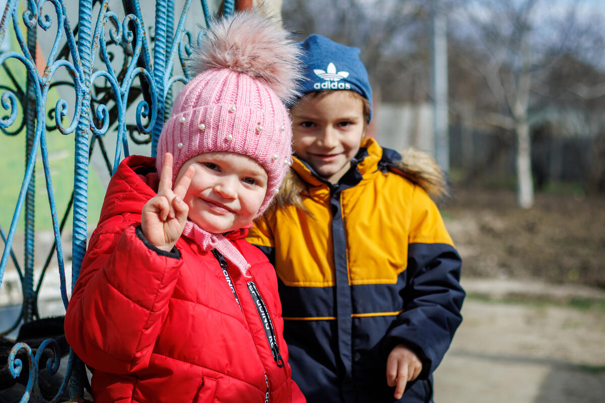 Two young children, dressed warmly, smile to the camera.