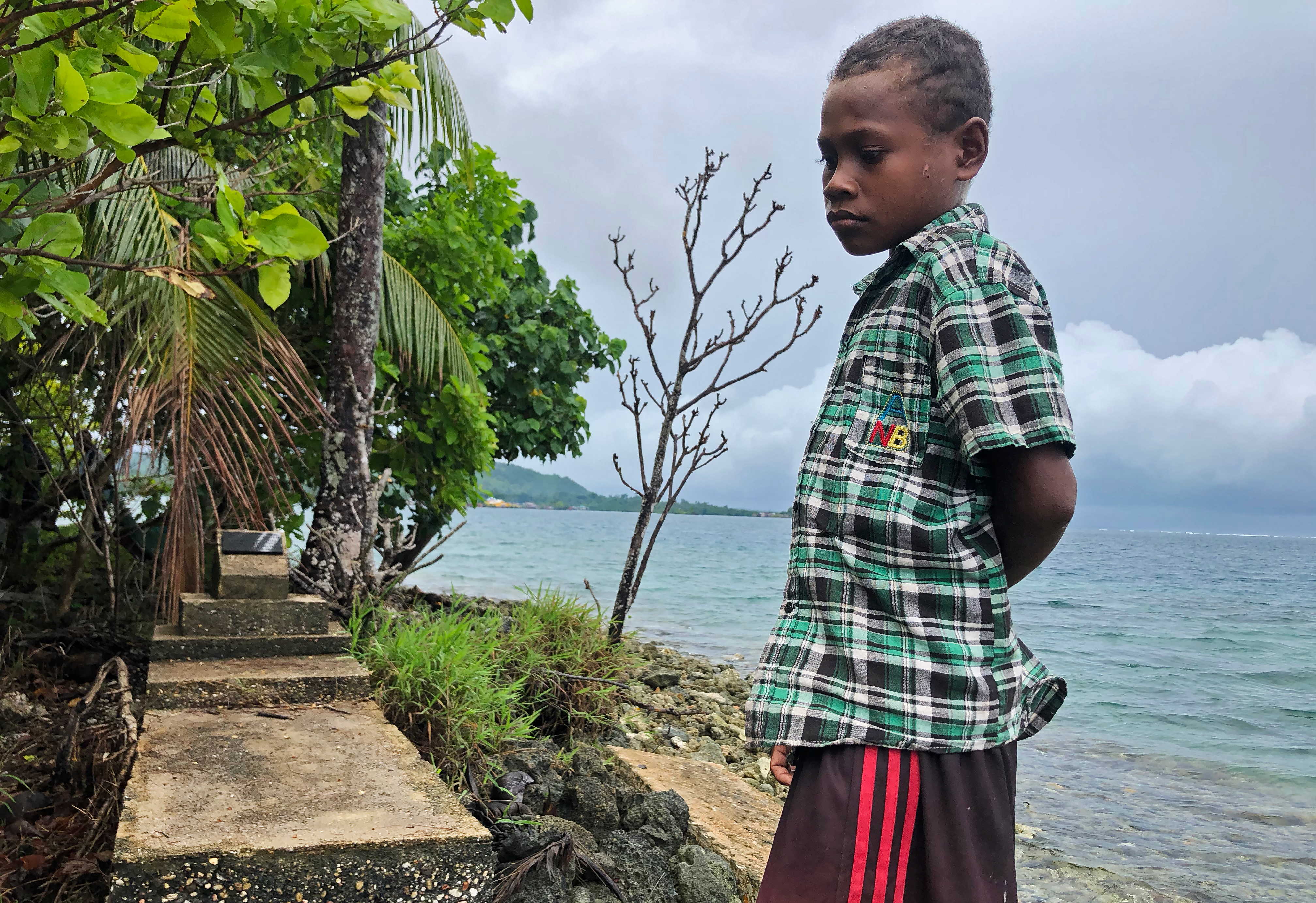 A boy stares sadly at the eroding island his family had to abandon