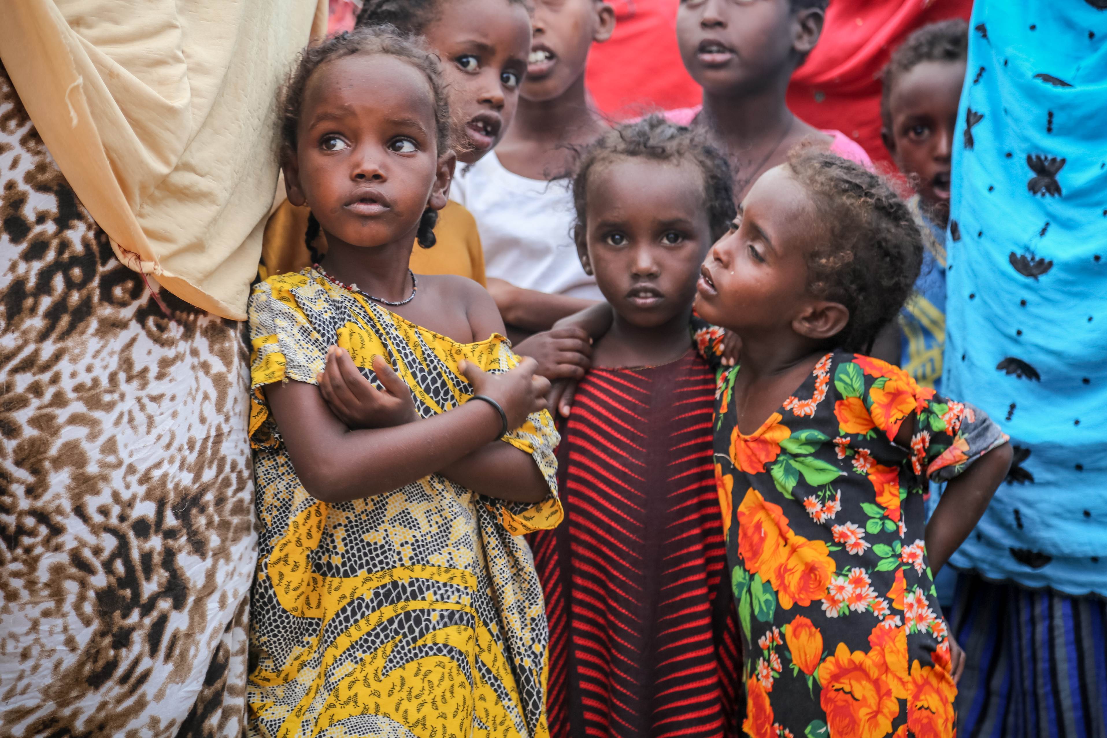 Three young hungry children in Somalia stand together in a crowd