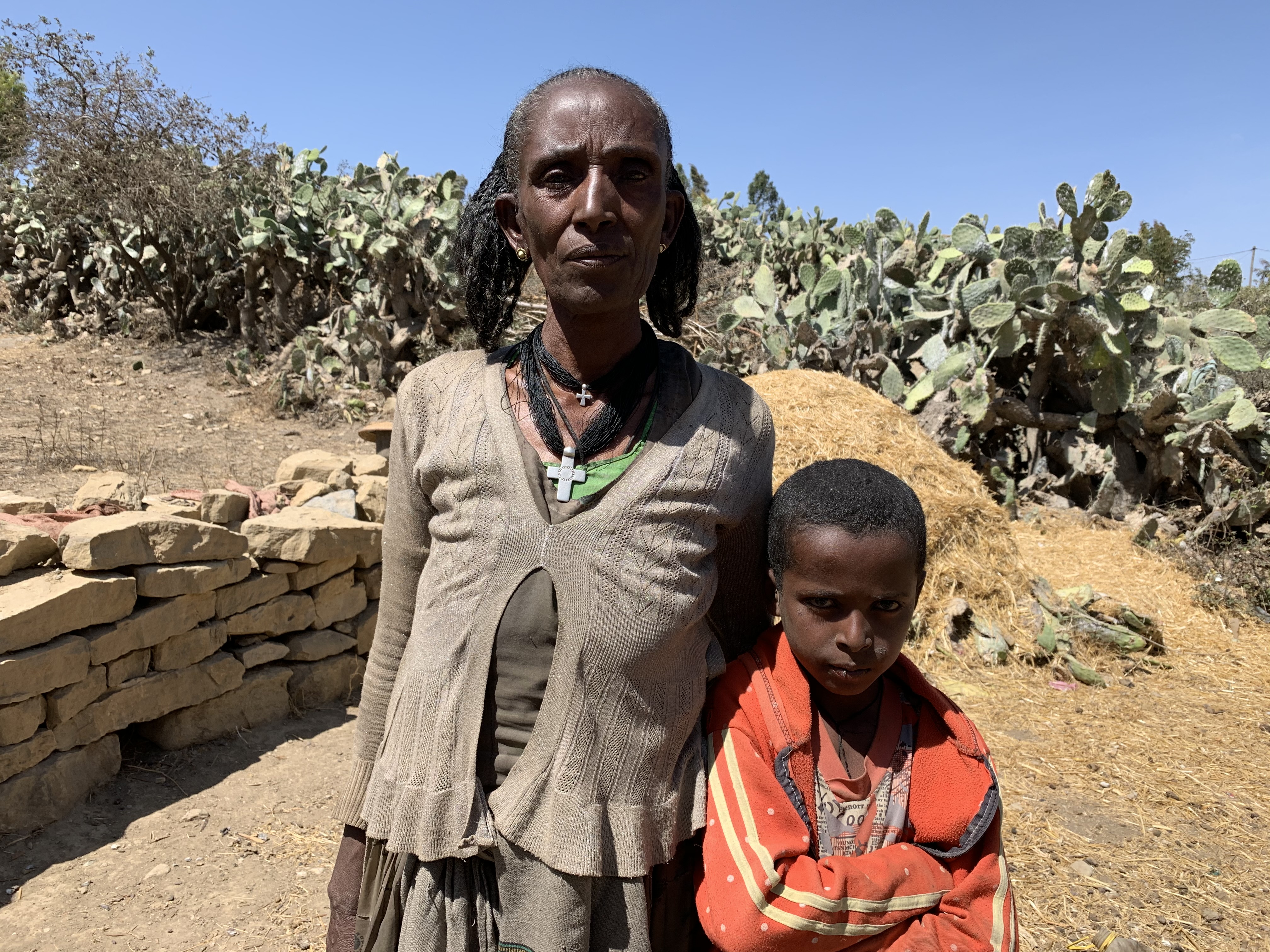Woman in Tigray, Ethiopia stands outside with her grandson, both having been displaced due to conflict