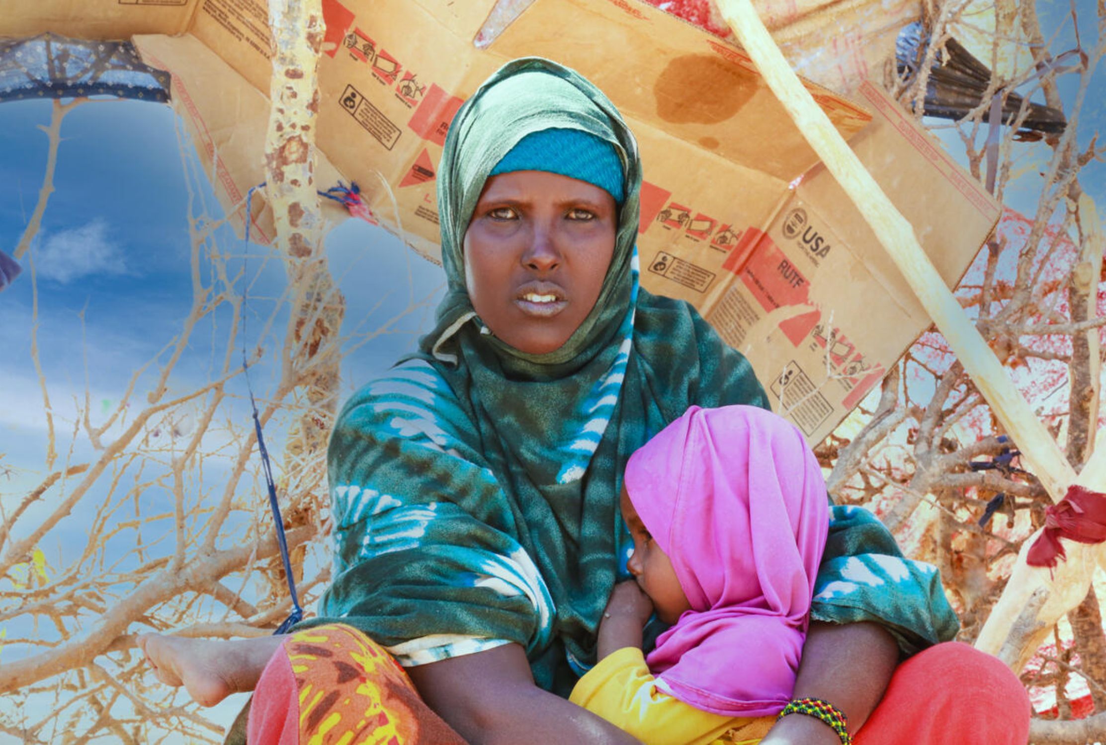 Somali mother holding her child while sat in front of a makeshift tent in an internally displaced persons camp