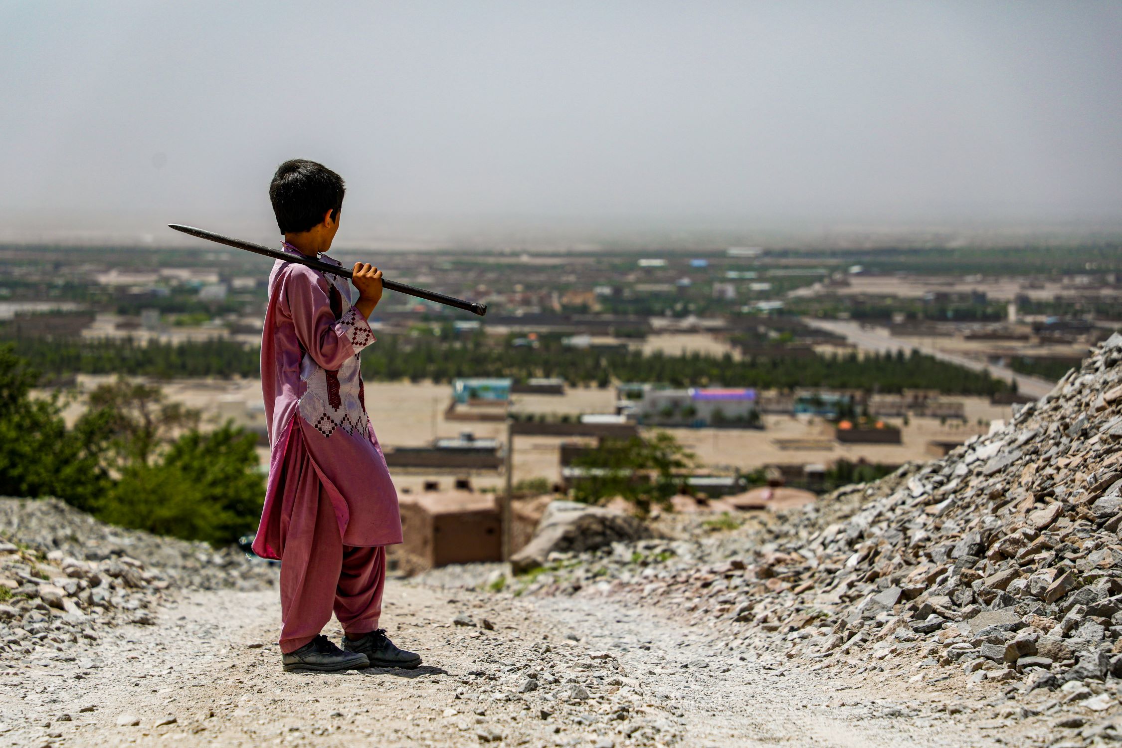 Afghan boy standing above town