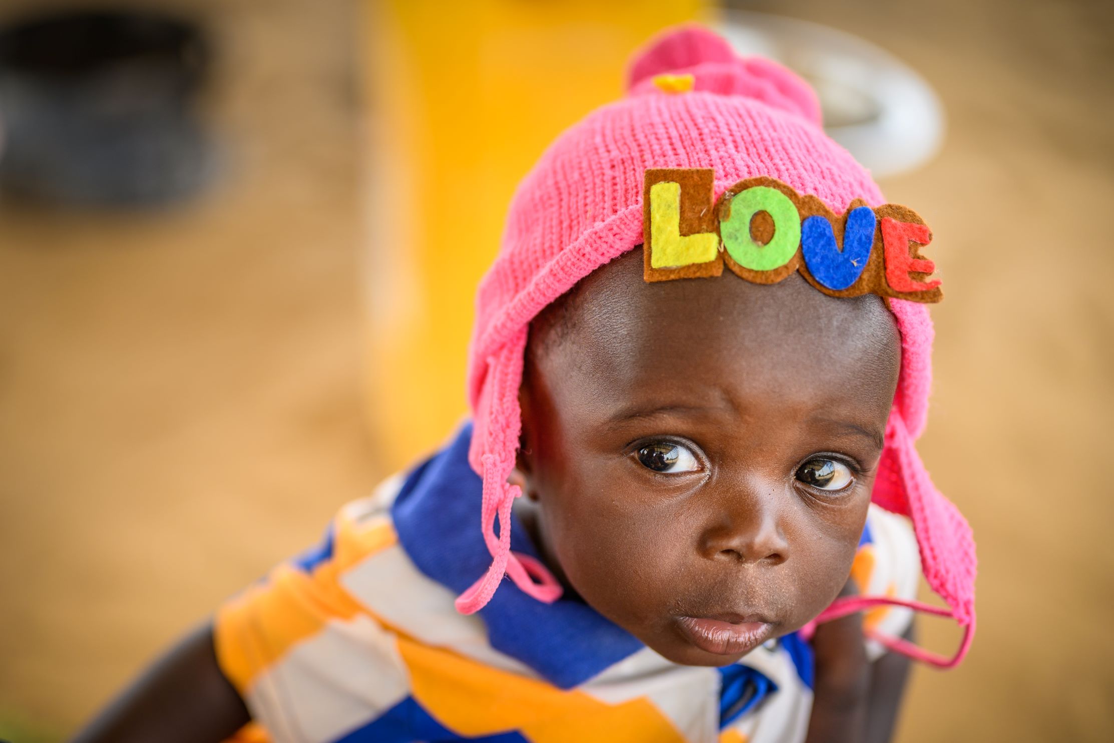 Baby wearing love beanie at health centre, Niger