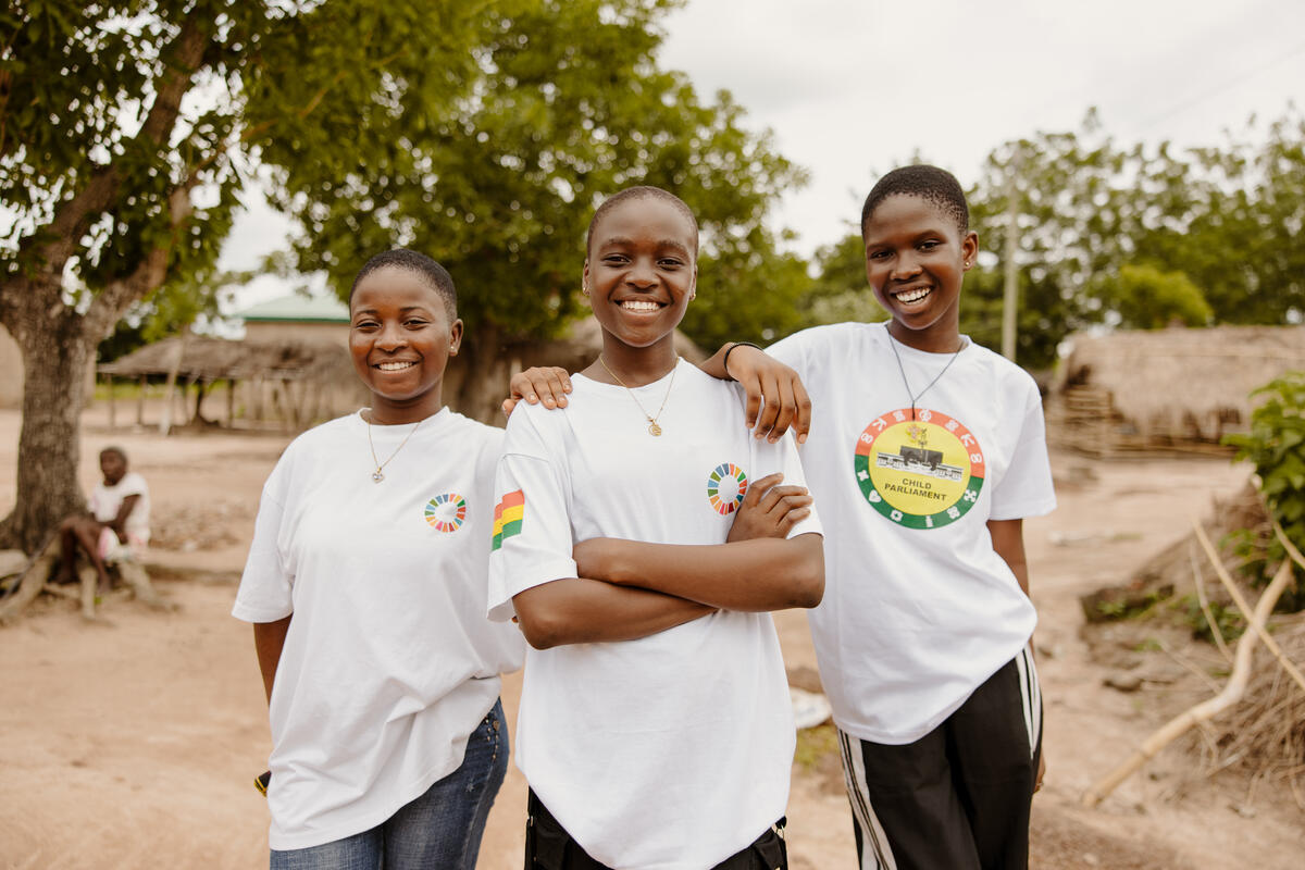 Princess stands facing the camera. Two girls stand either side, resting an arm on her shoulder.