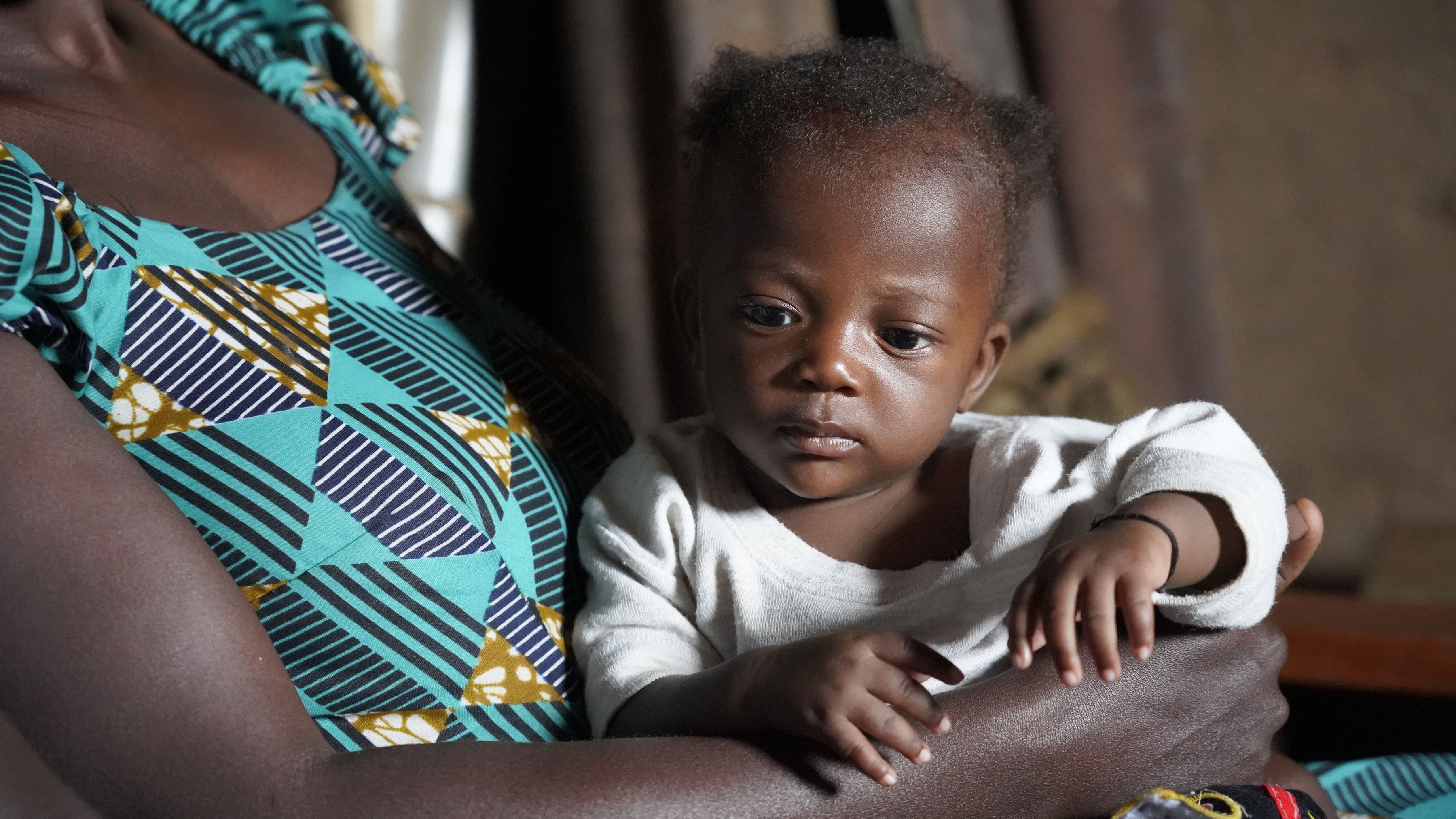 A 7 month old in the DRC sits in the loving arms of his mum