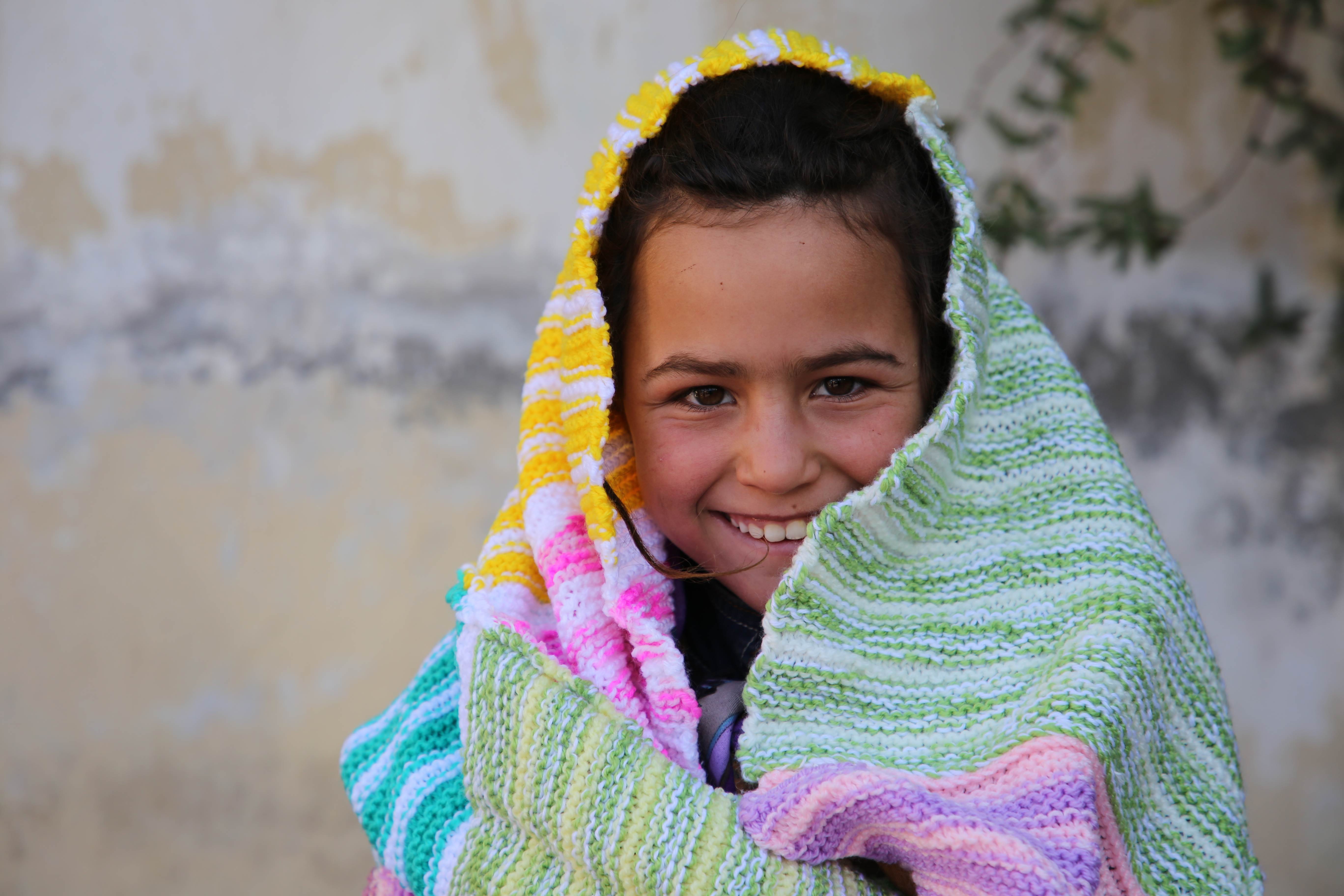 A young girl wrapped in a blanket and smiling