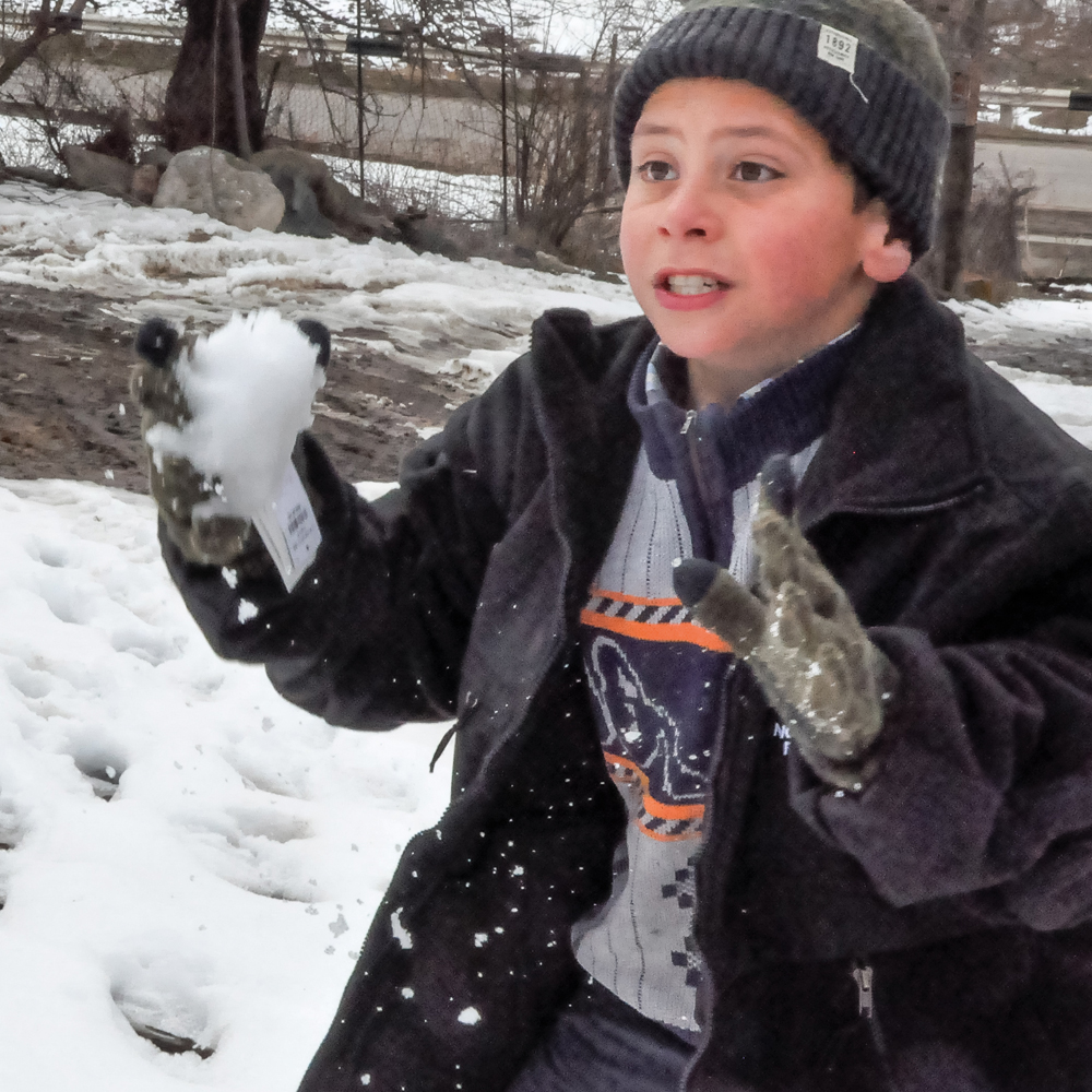 Boy throwing snowballs in cold weather