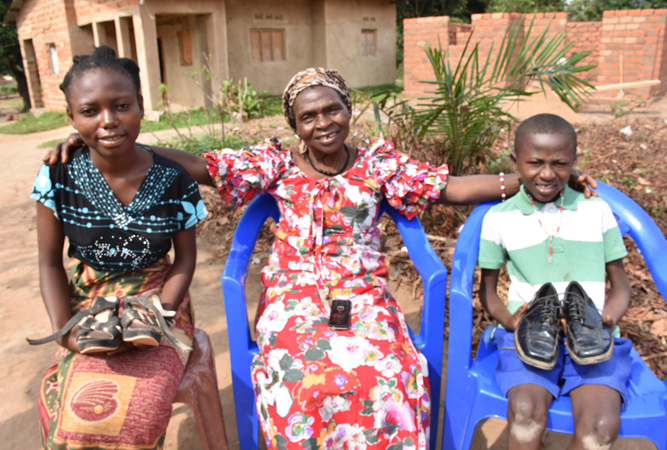Congolese grandmother and two grandchildren holding their new shoes