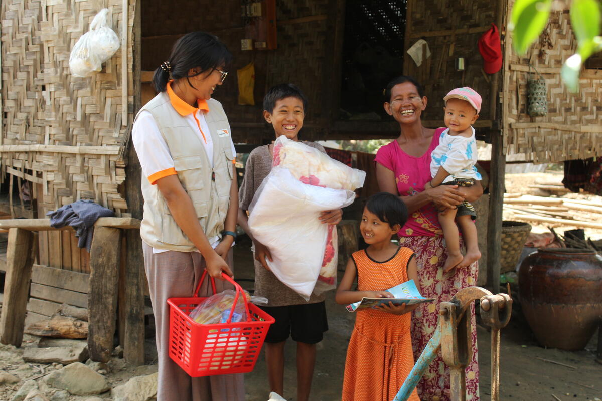 Mother and toddler smiling, holding food supplies.
