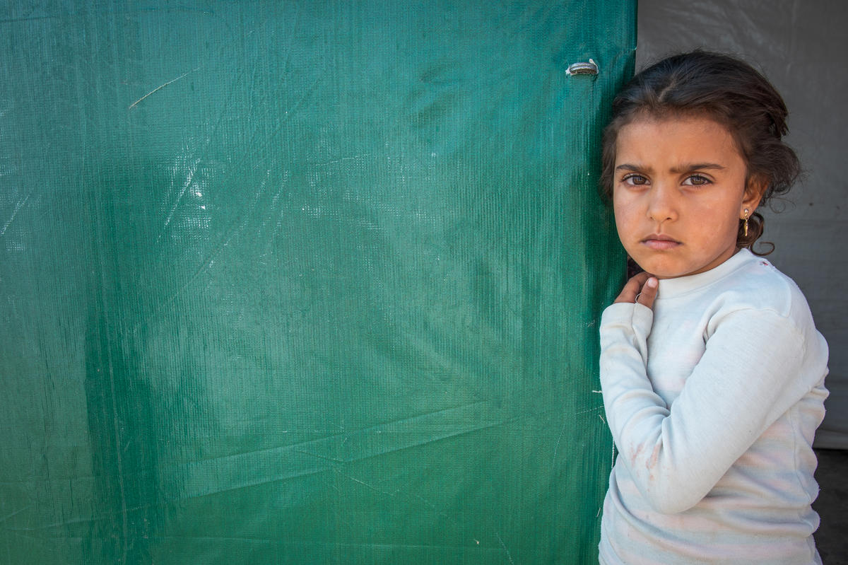 A young Syrian girl stands in a refugee camp