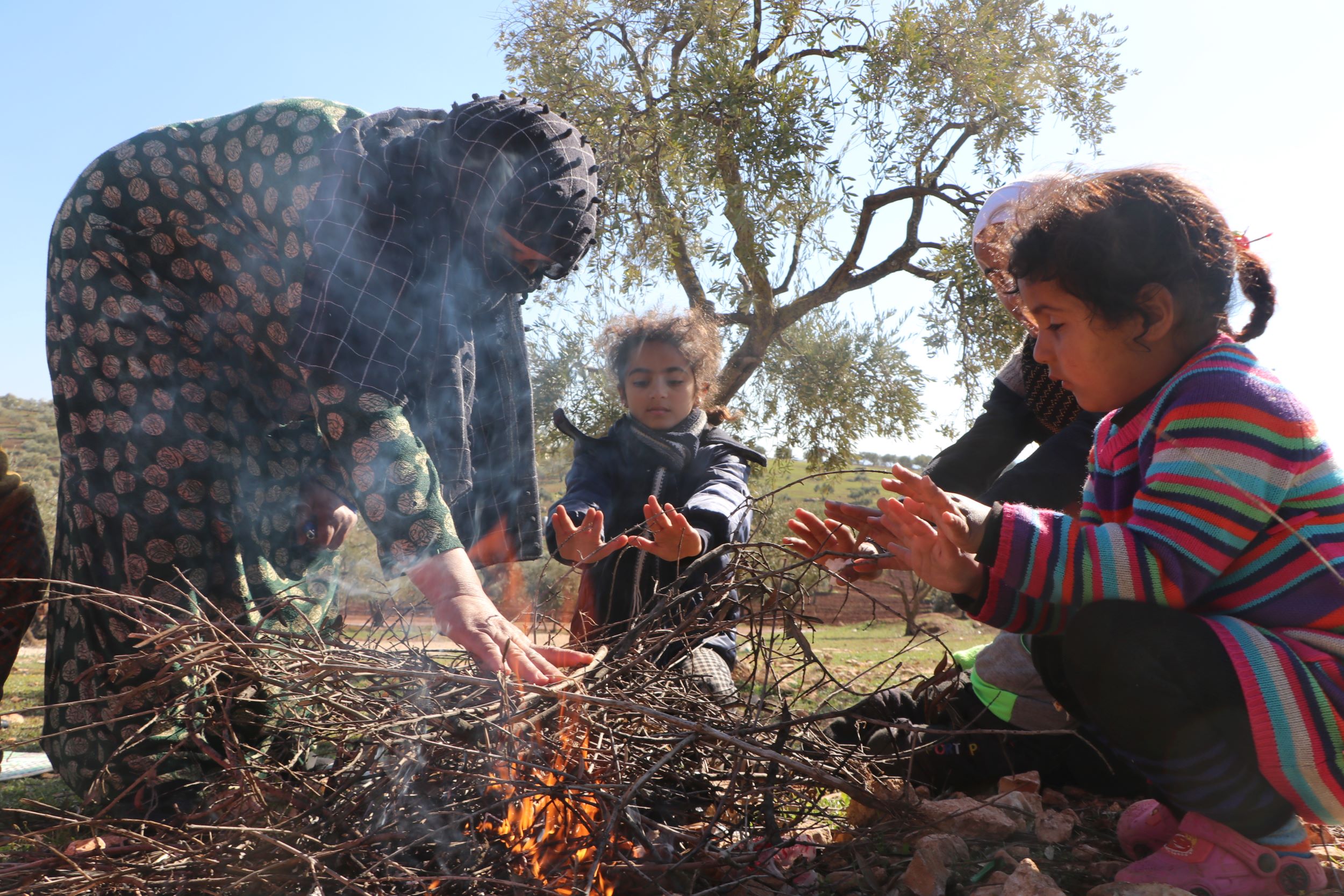 A Syrian family huddle around a fire to keep warm