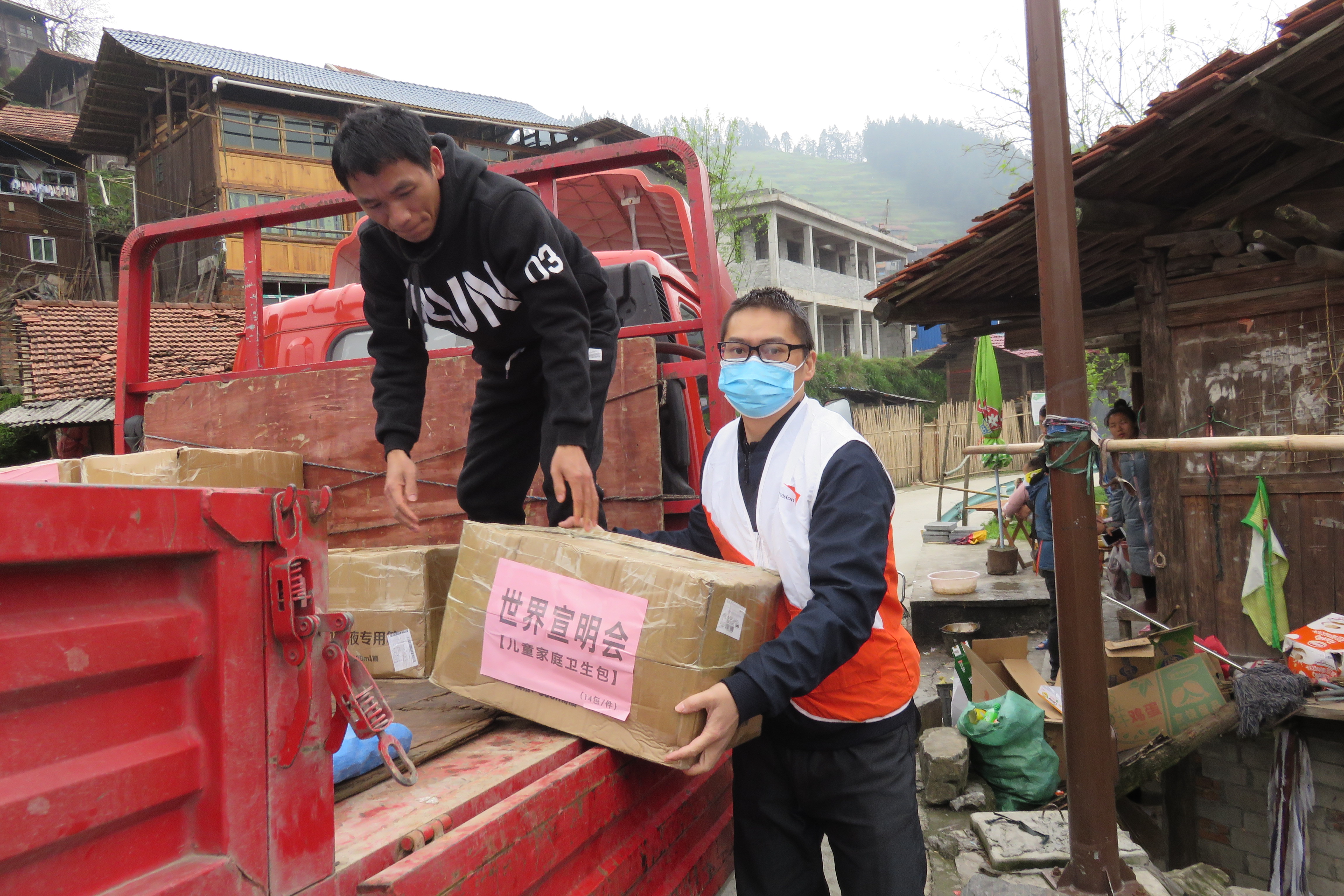 World Vision staff member in China wears a mask as he unloads a box of medical supplies like thermometers for a community