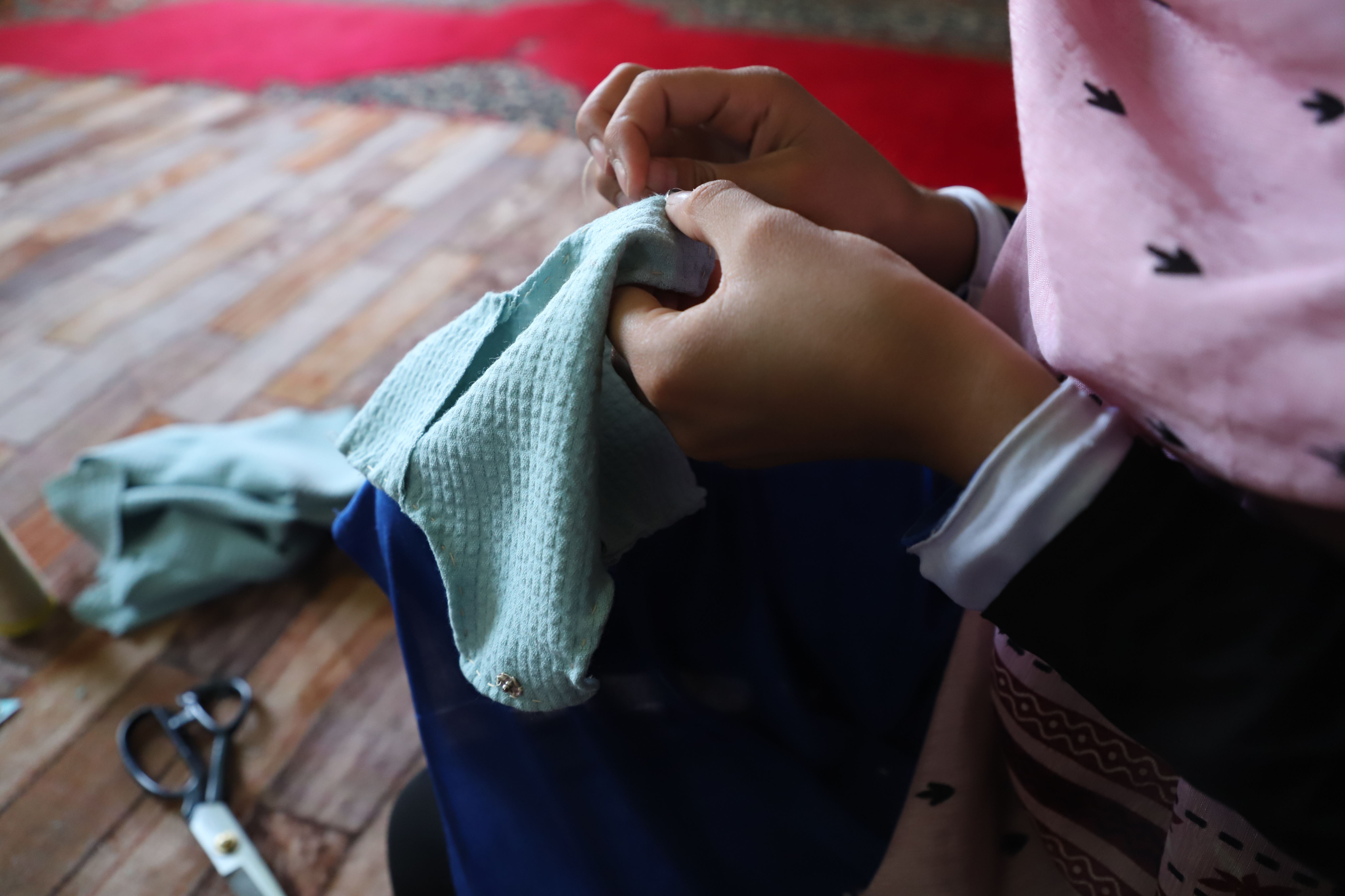 A child in Afghanistan making a reusable menstrual pad by hand.