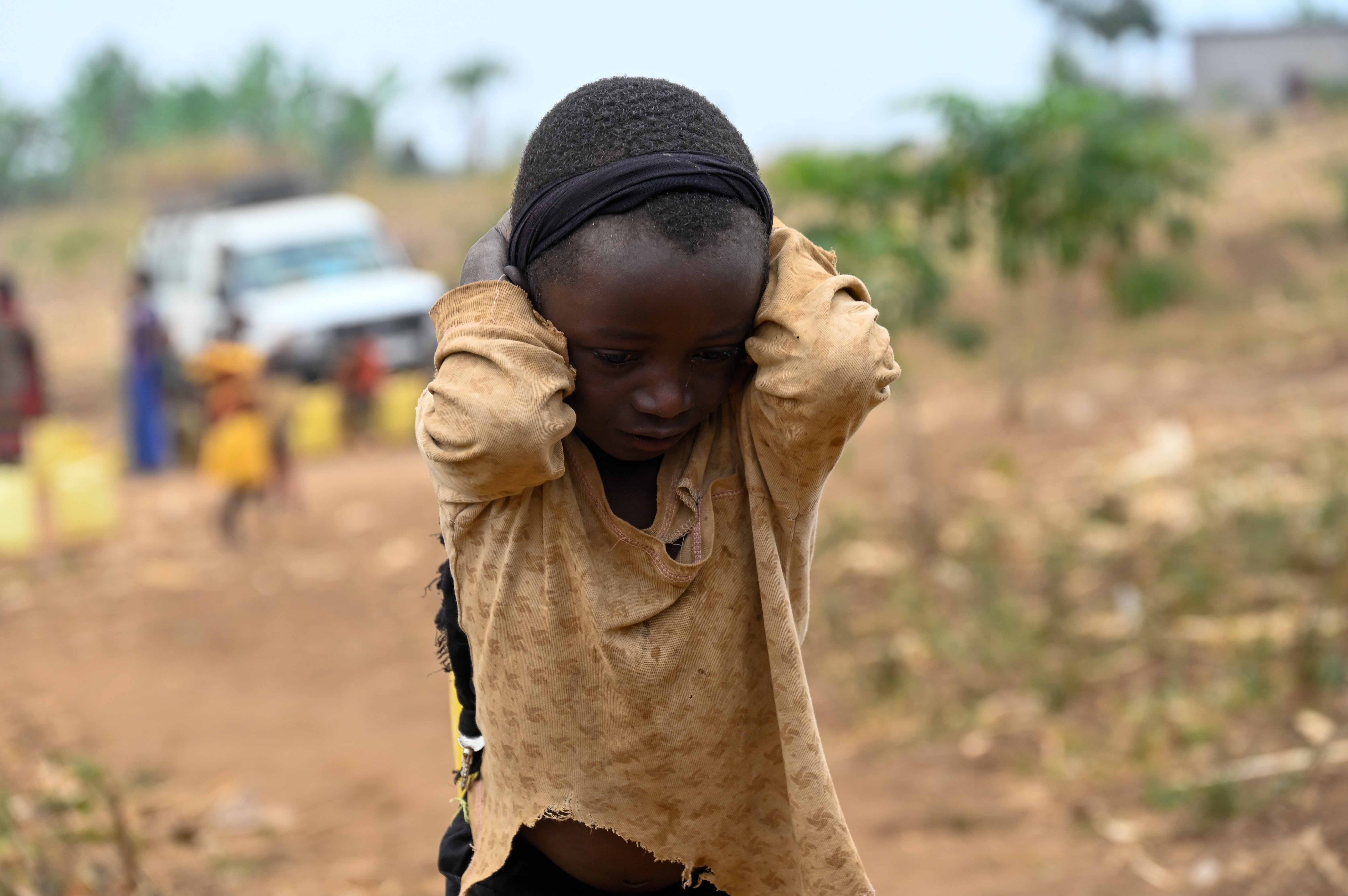 Ugandan refugee child holding his ears to block out noise