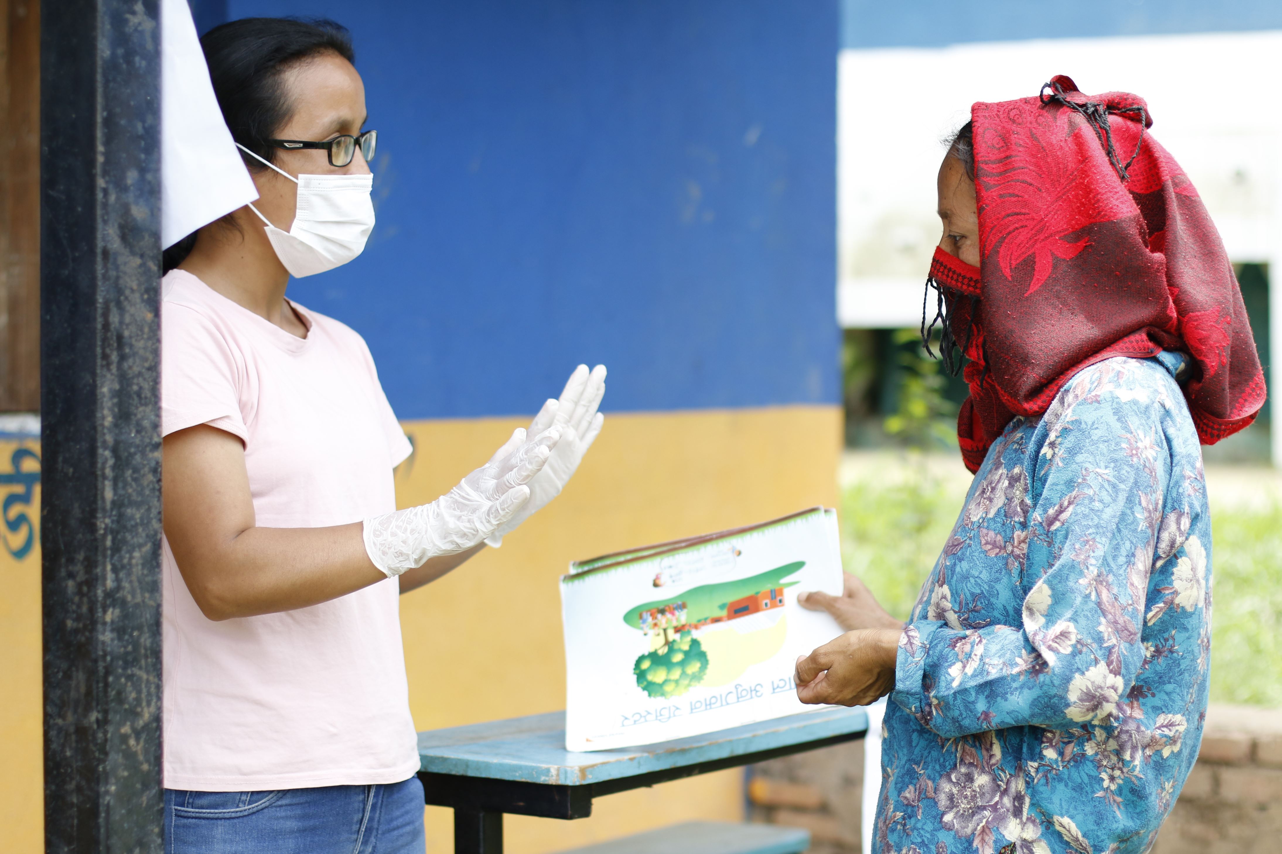 Health worker in Nepal talks to a woman and holds out information