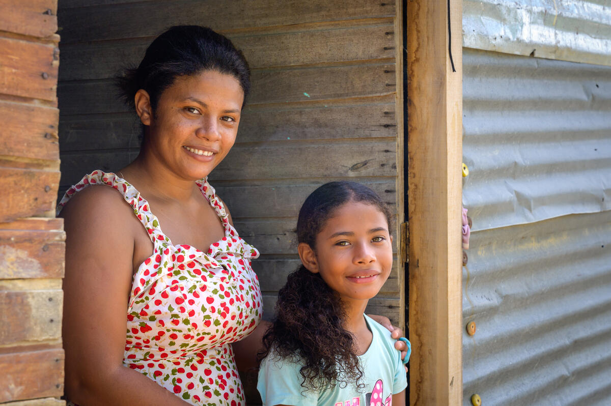 Girl from Colombia smiles in a doorway with her mother