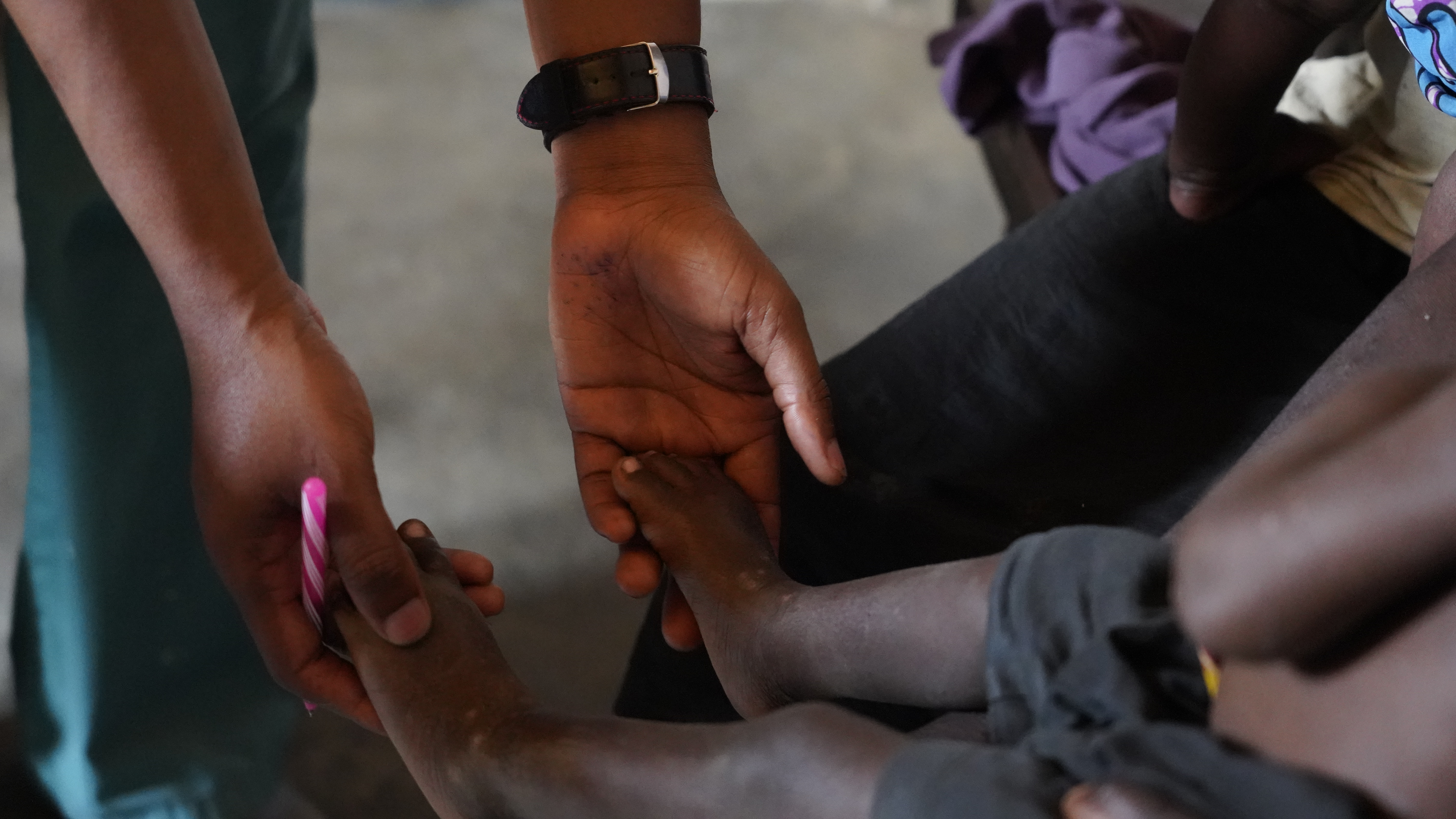 A young child sat on their mothers lap while a doctor reviews their progress