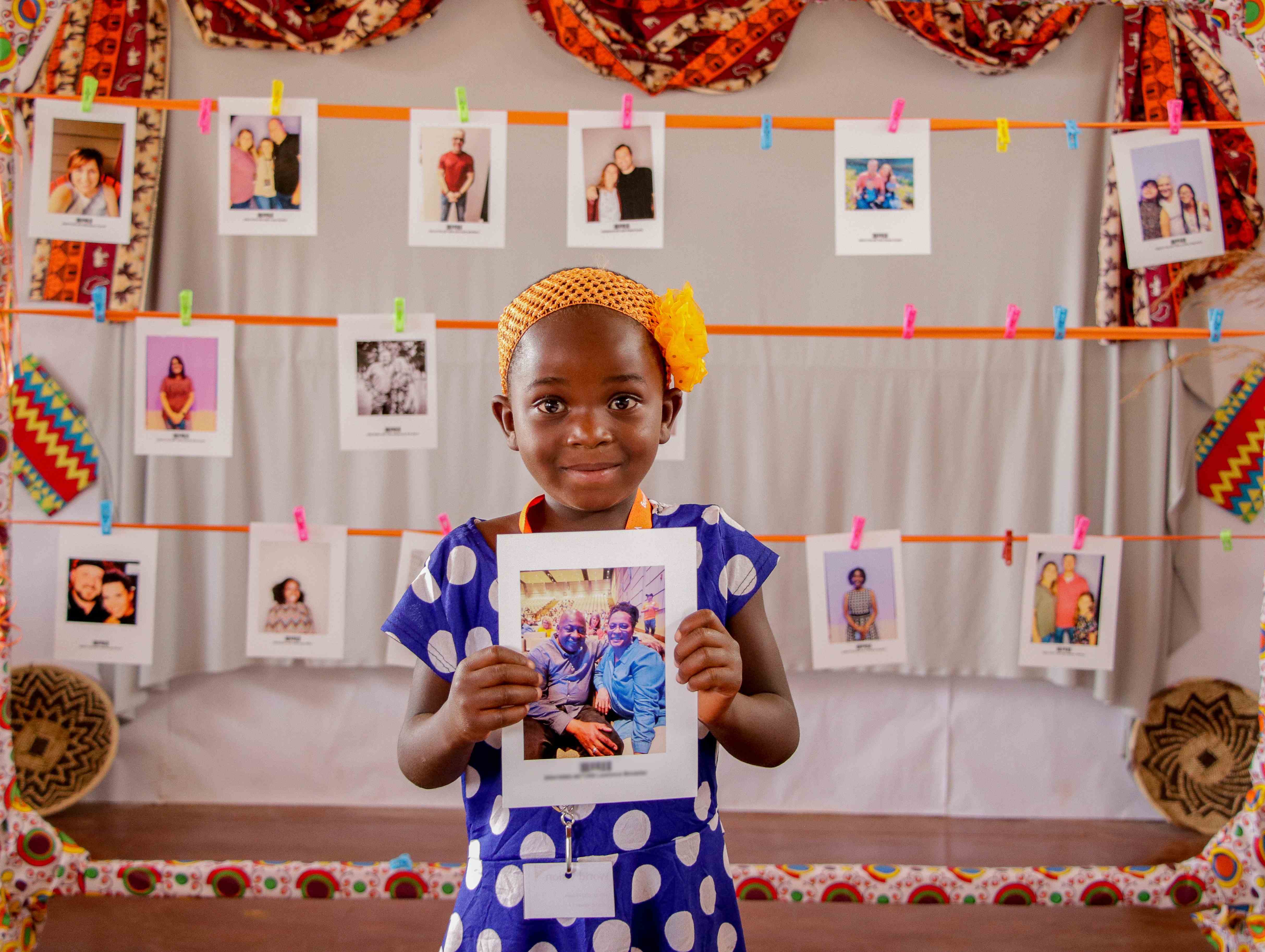 Young girl holds a photograph of a sponsor that she's just chosen. 