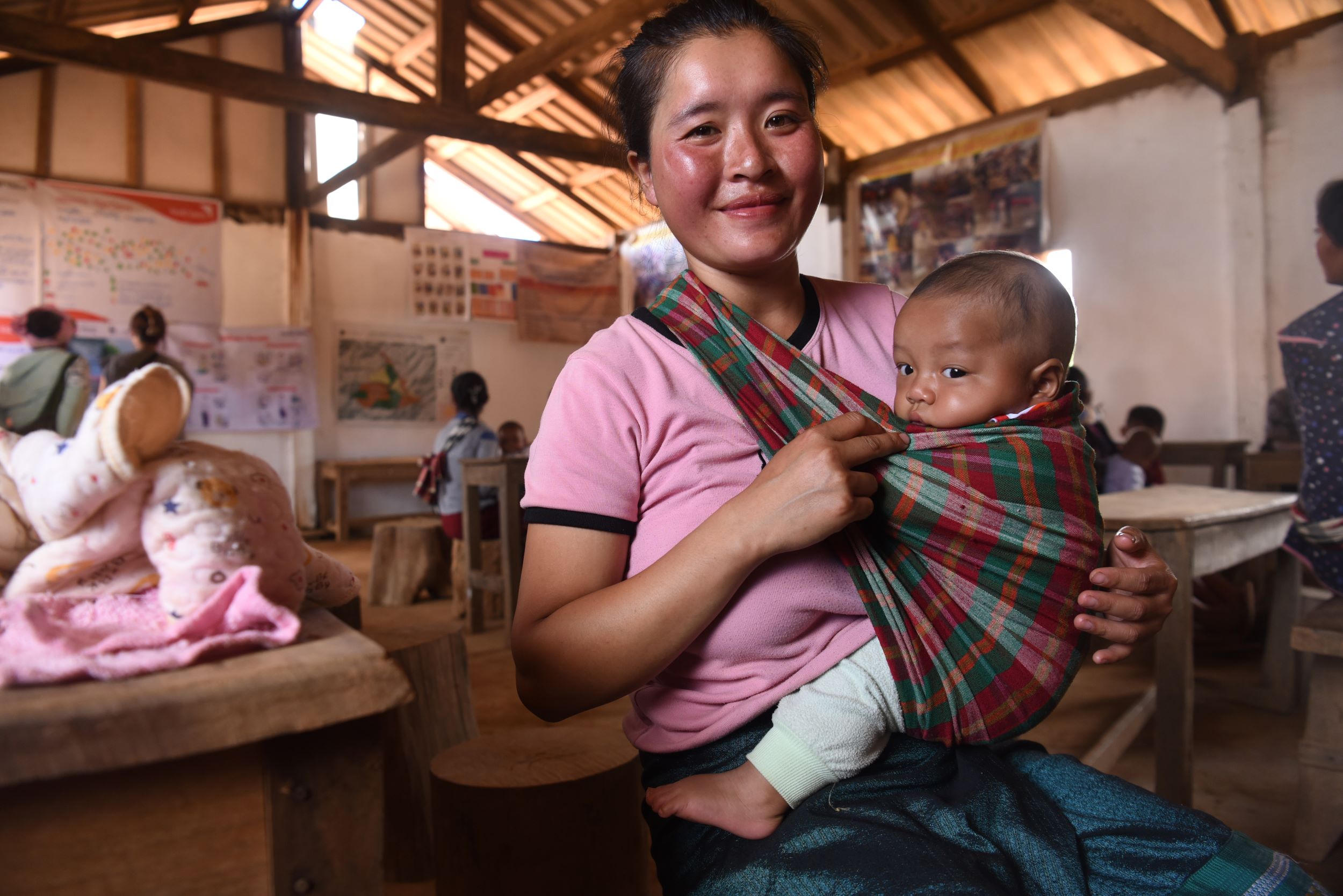 Smiling mother carrying her baby in a sling, Laos
