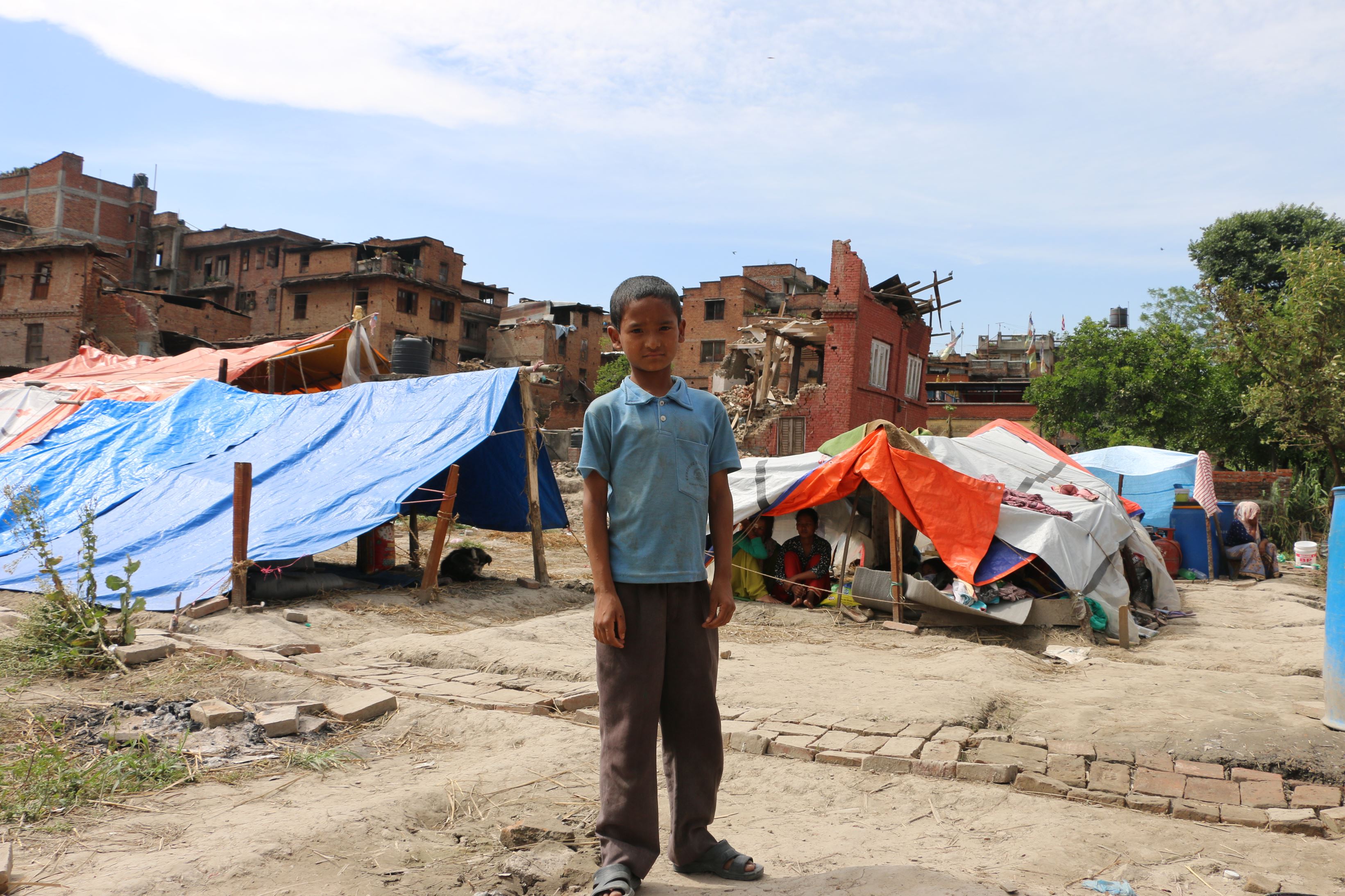 Boy in front of aftermath of earthquake in Nepal