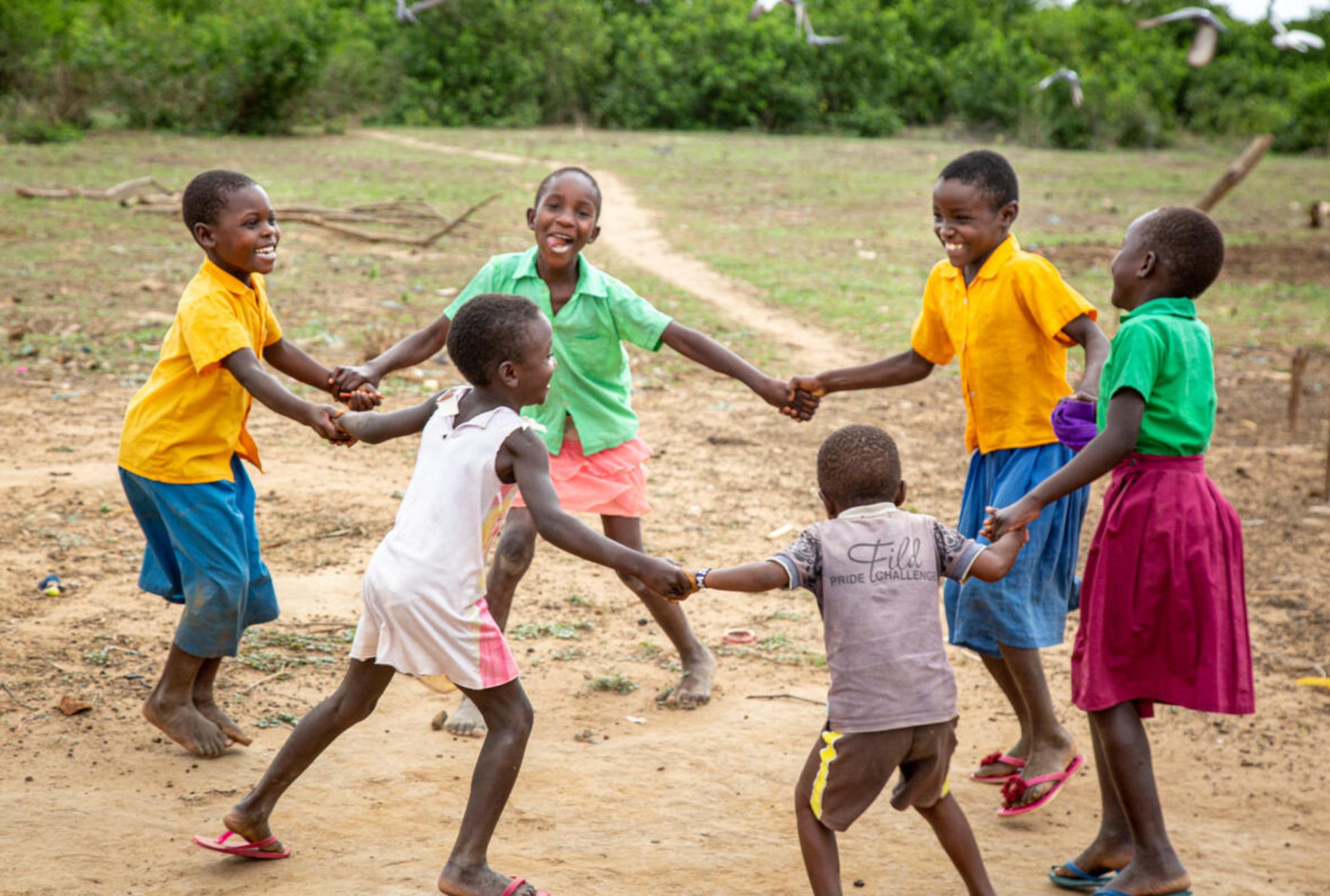6 Kenyan children enjoy playing happily, holding hands and skipping around in a circle