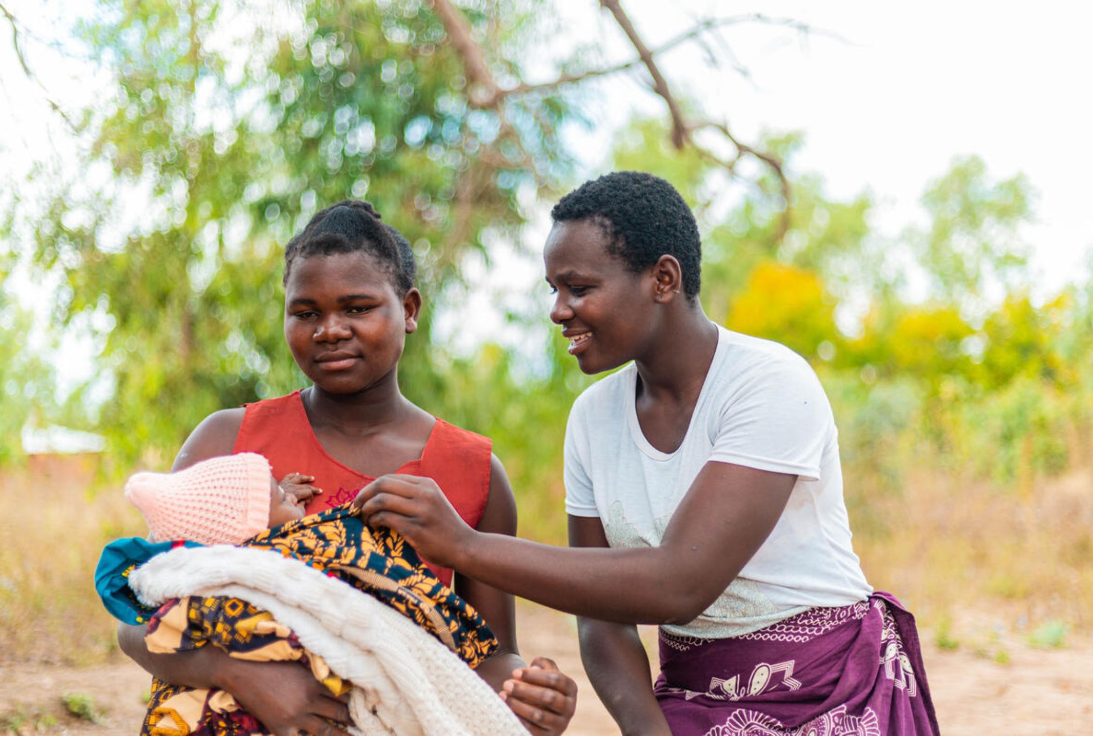 Girl from Malawi helping another girl holding her newborn baby