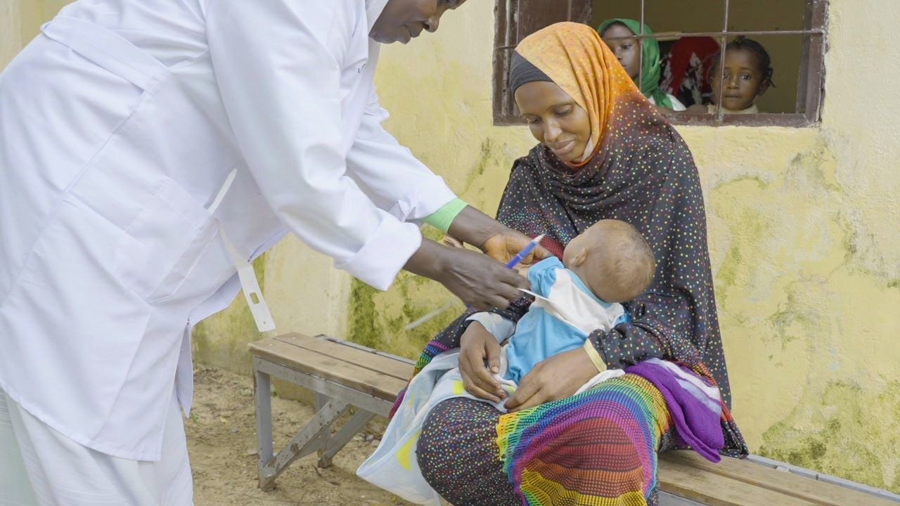 Sudan mother taking her baby to World Vision mobile clinic