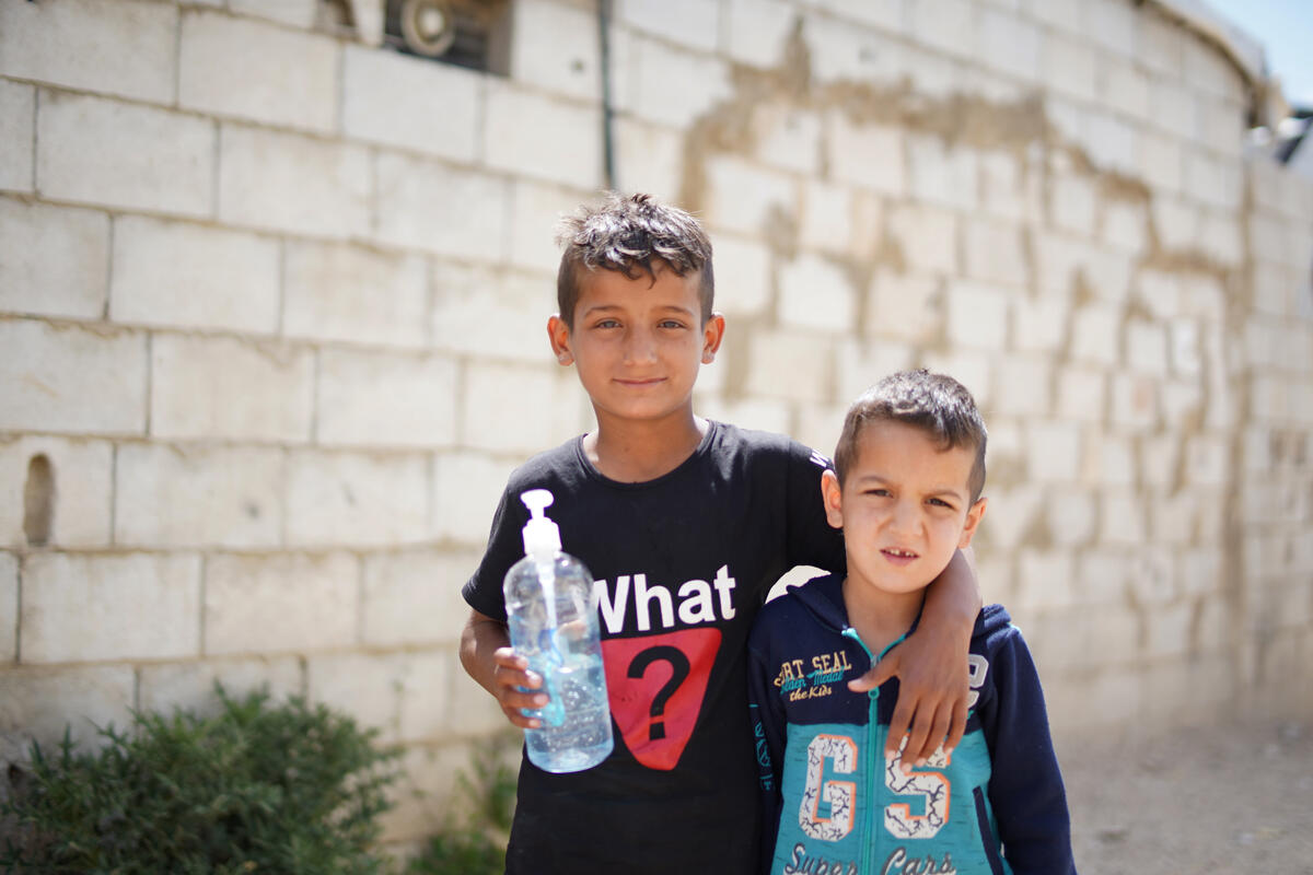 Two Syrian boys, the older one holding a plastic bottle