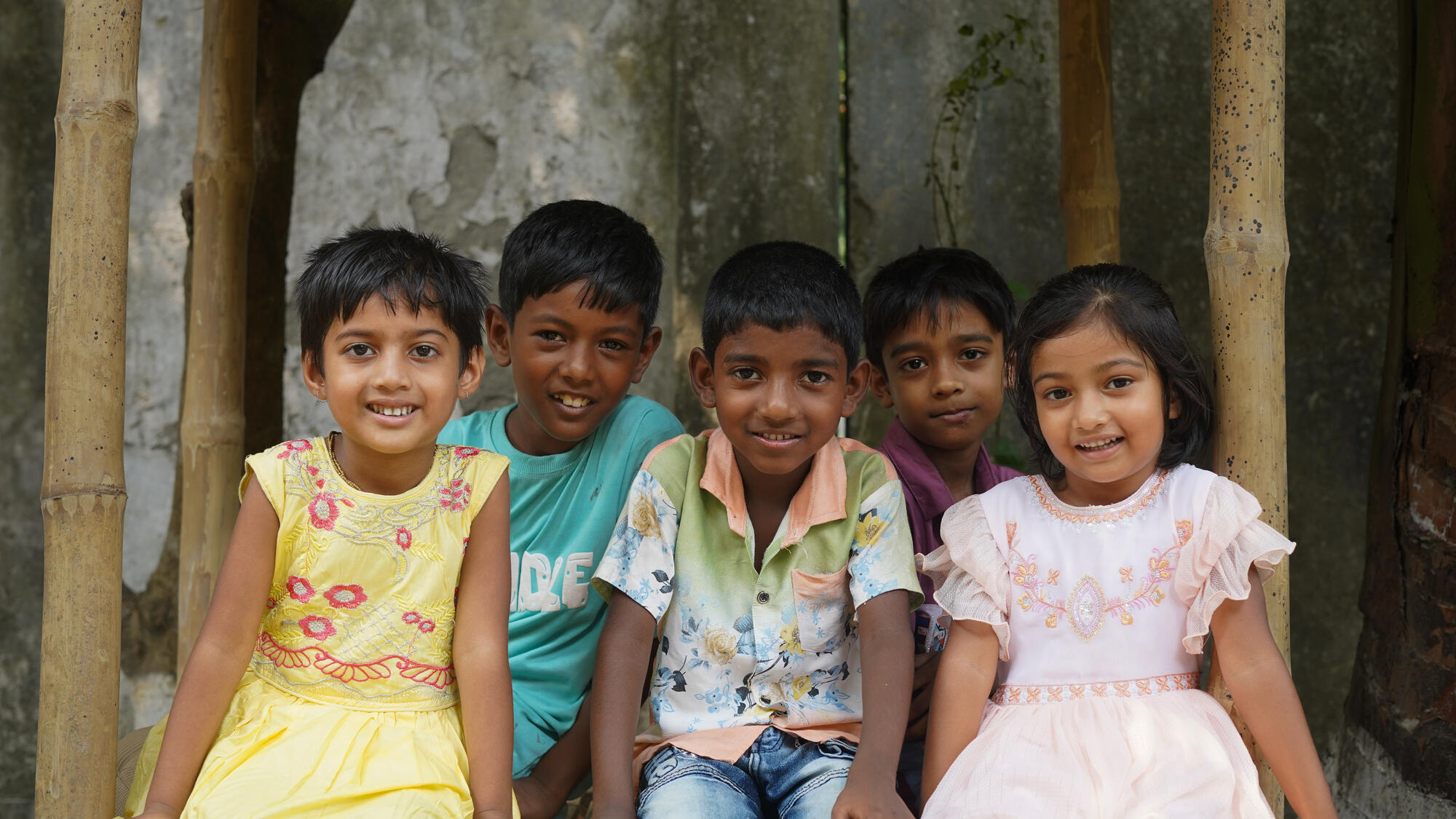 Five young children from Bangladesh smile directly to the camera