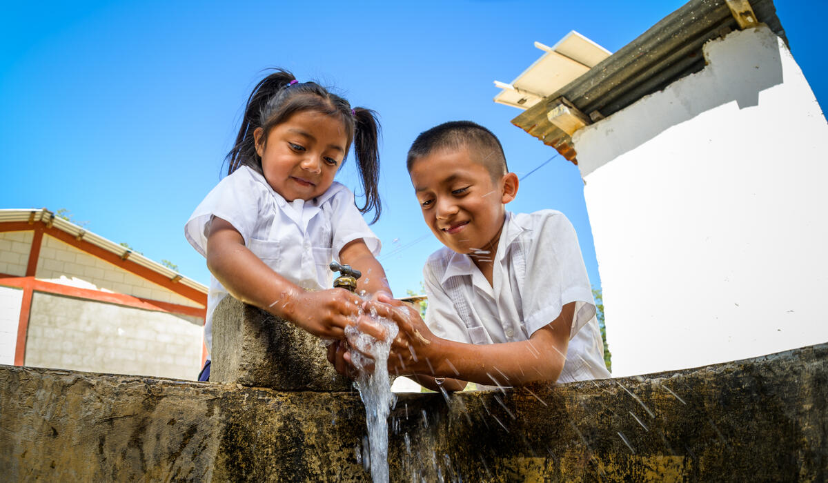 Sponsored girl and a friend in Honduras washes her hands in clean water brought by World Vision on her first day of pre-school