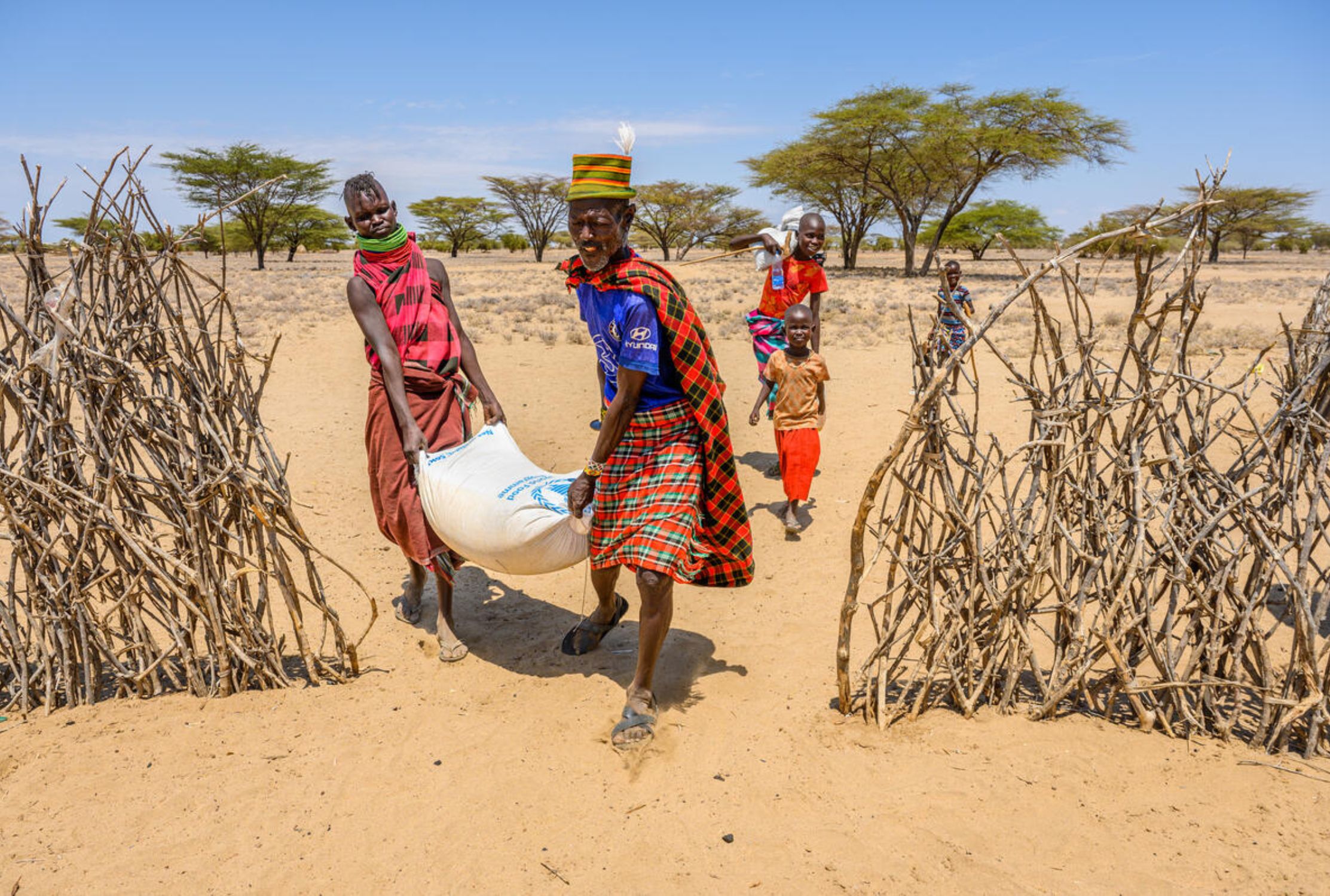 Kenyan husband and wife carrying a sack of food from World Vision's food distribution centre.