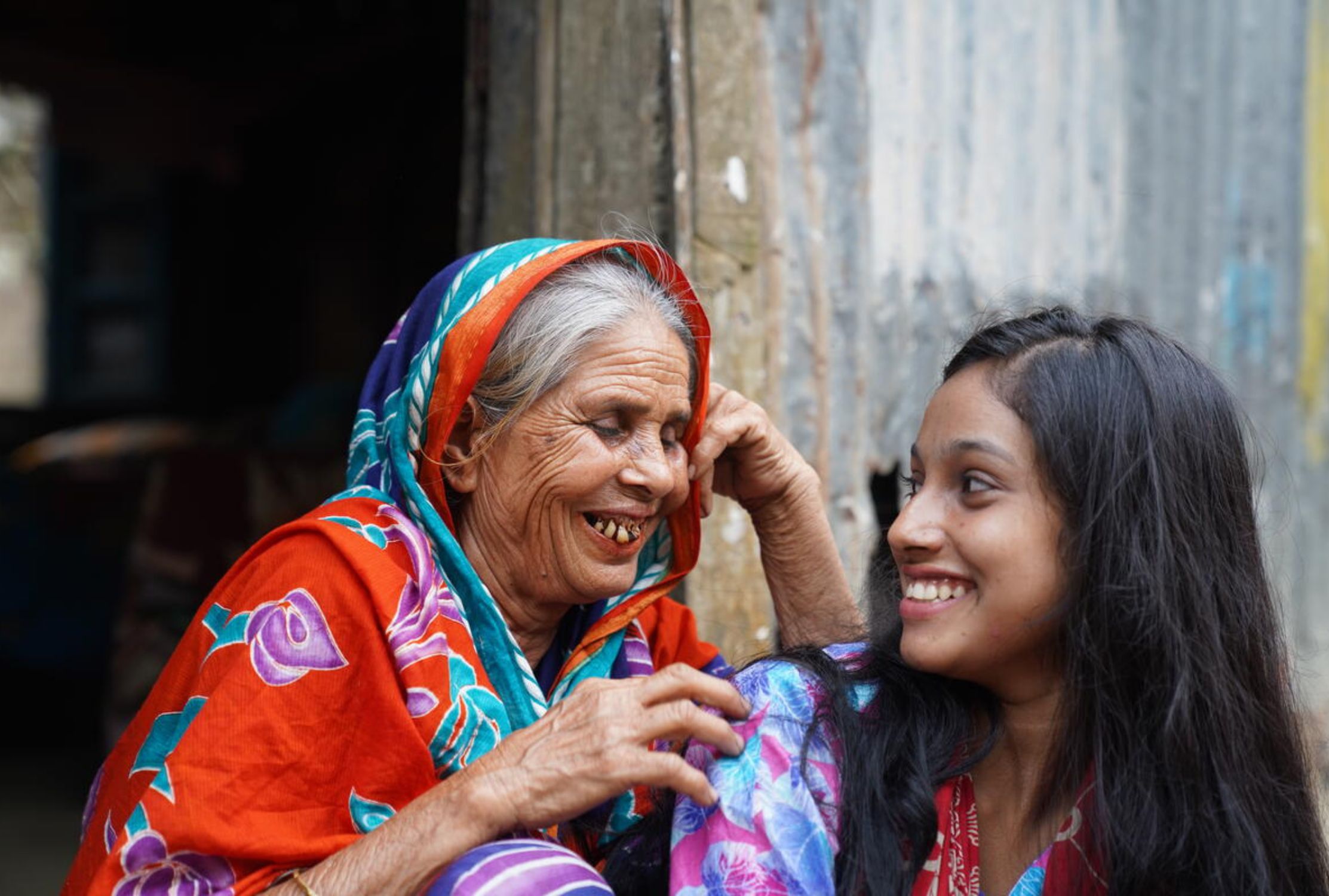 Girl from Bangladesh smiling at and older woman