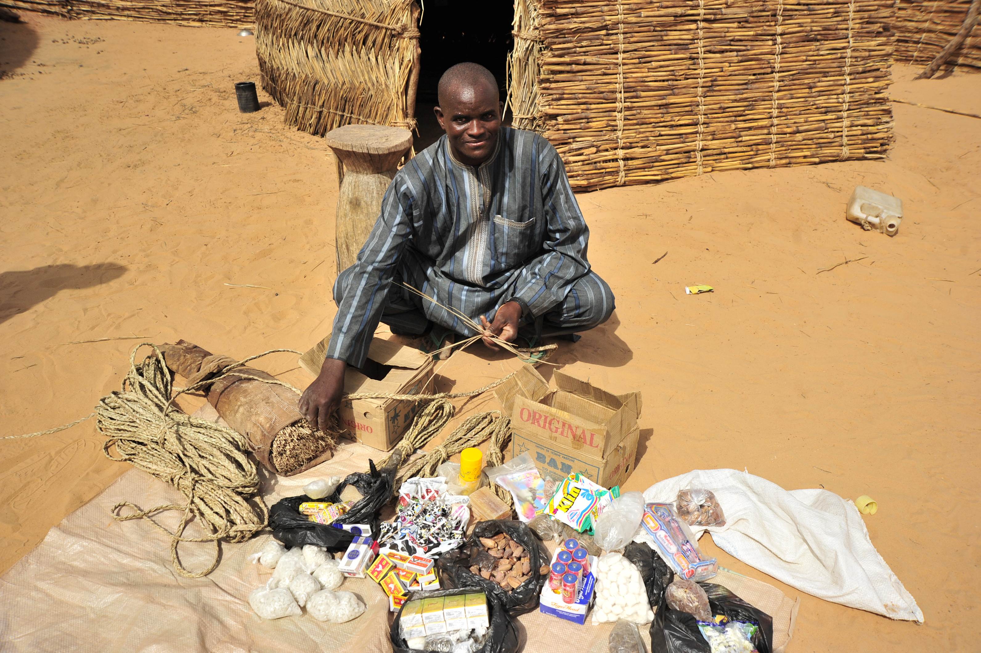Man in Niger sits outside in front of wares he is selling