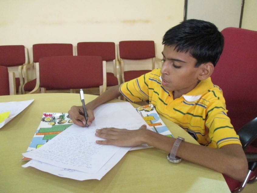 A boy sits at a table writing