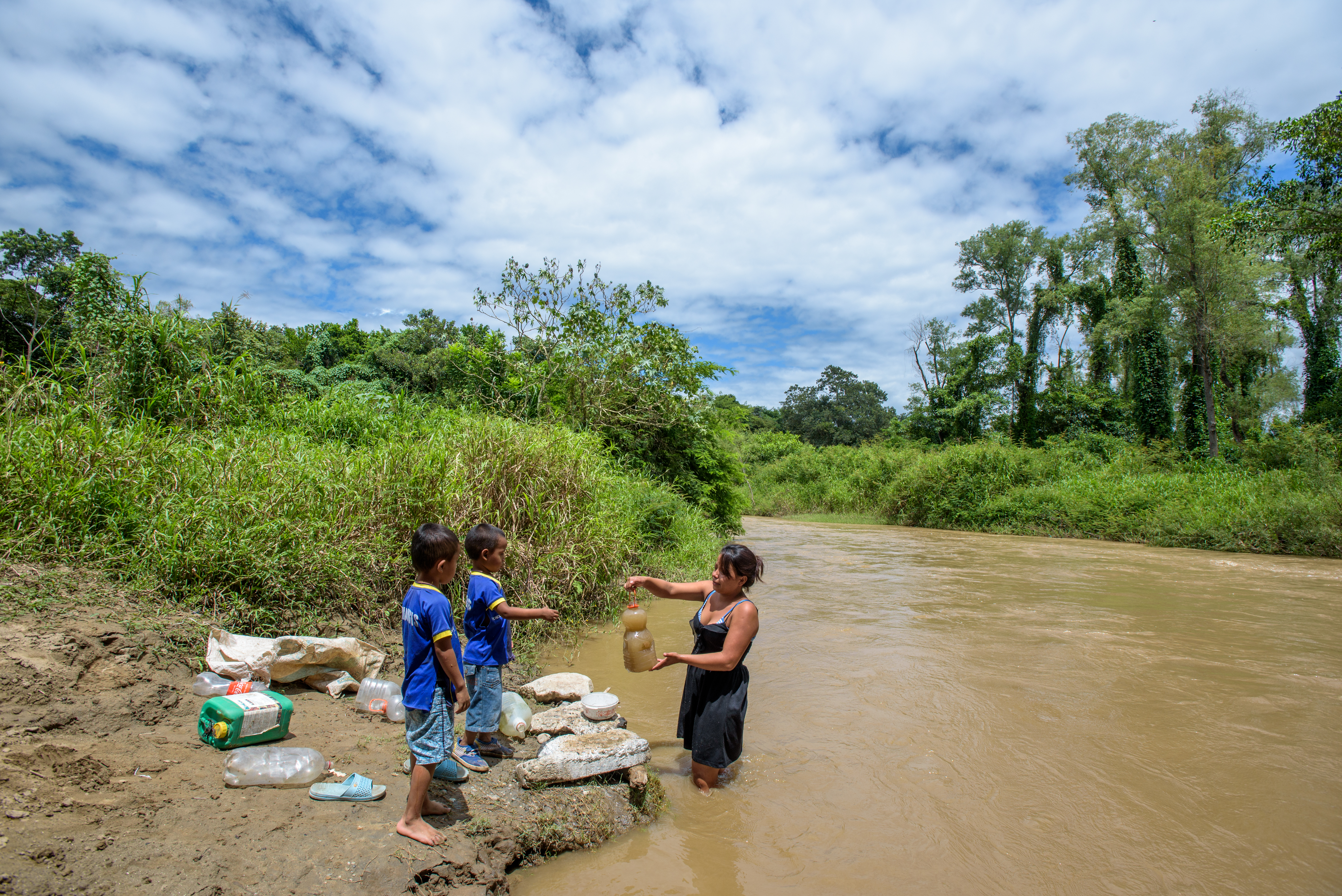 Family in Honduras collect water from a dirty river