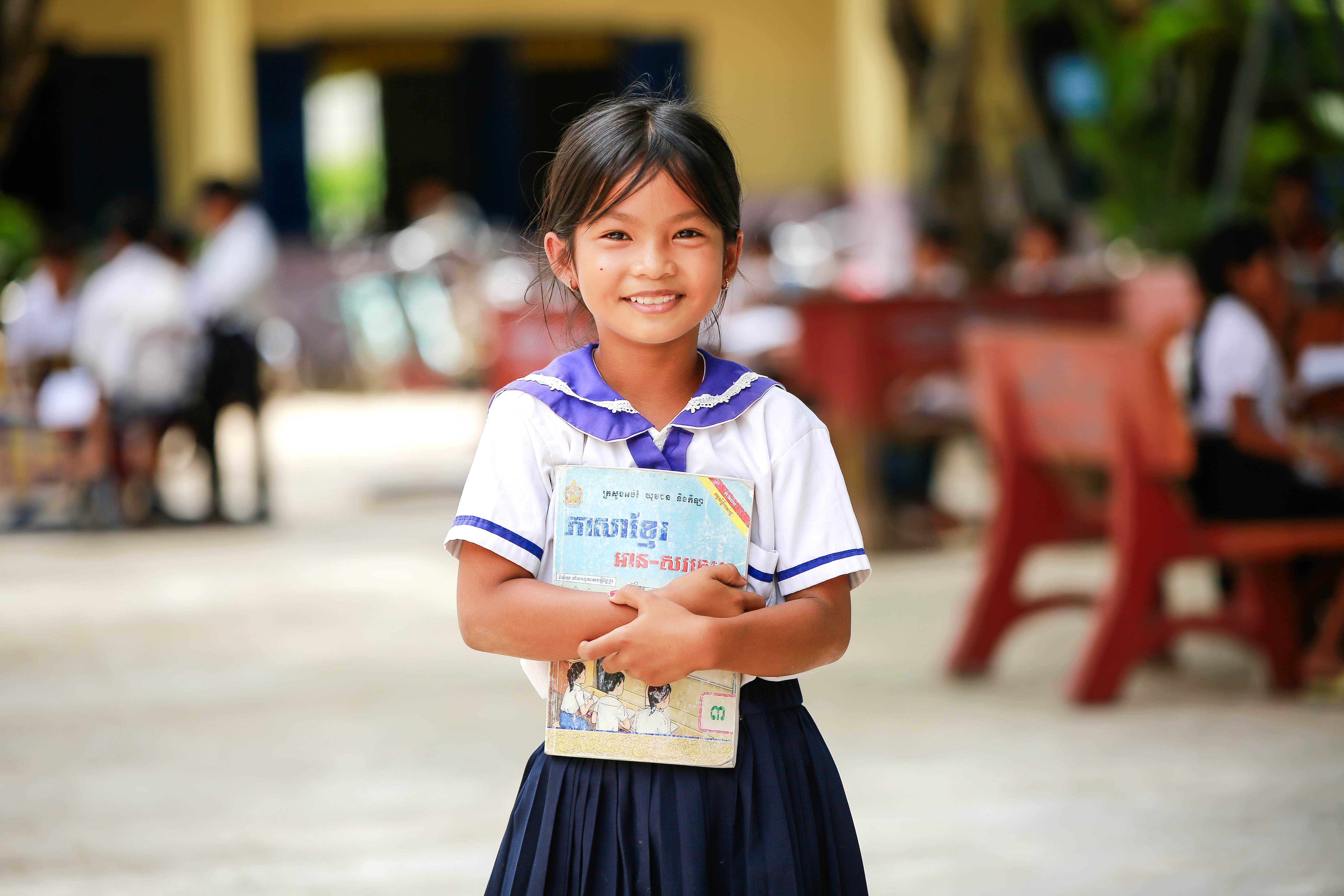Young girl smiles whilst holding a book