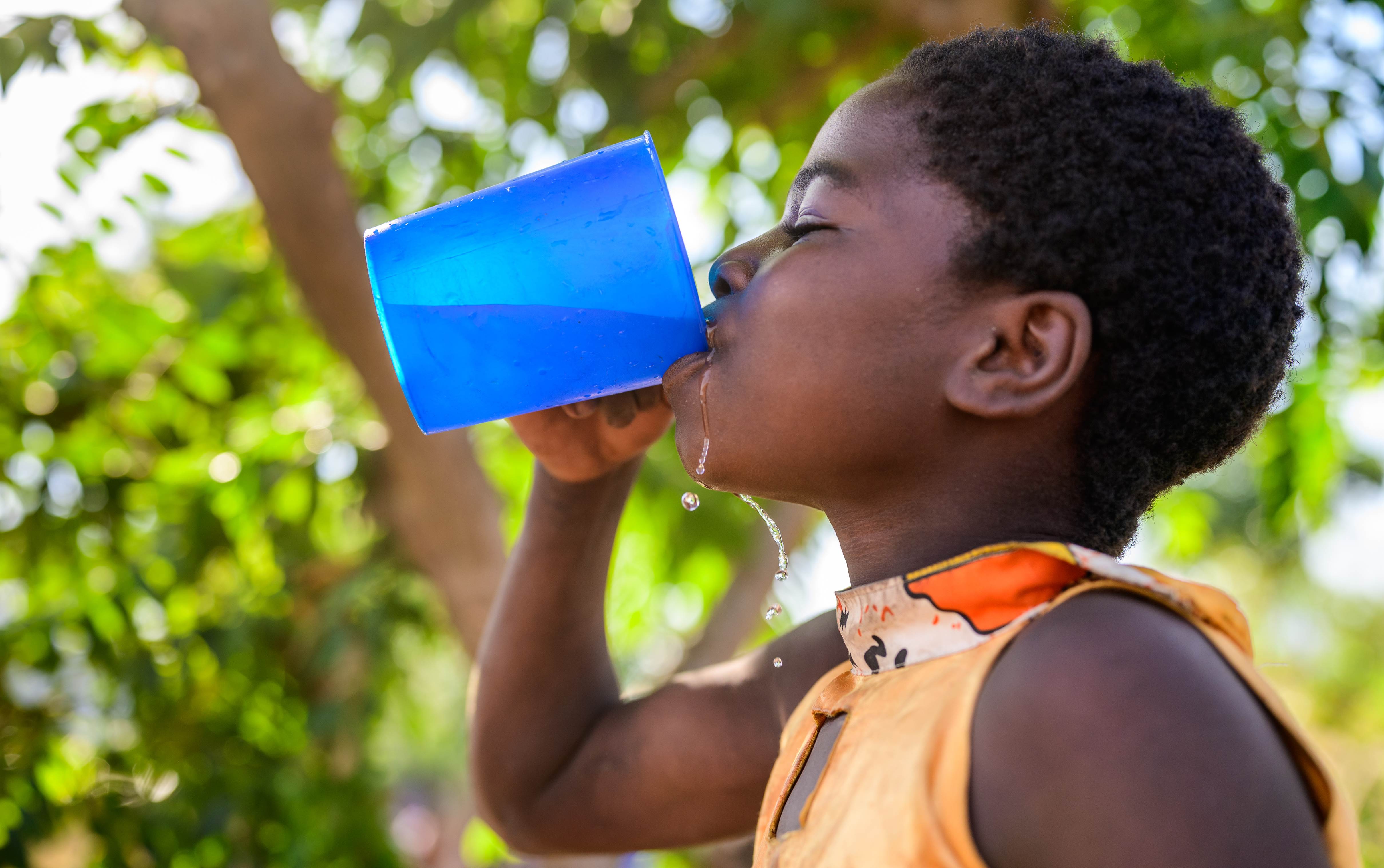 A girl in Malawi drinks a cup of fresh, clean water