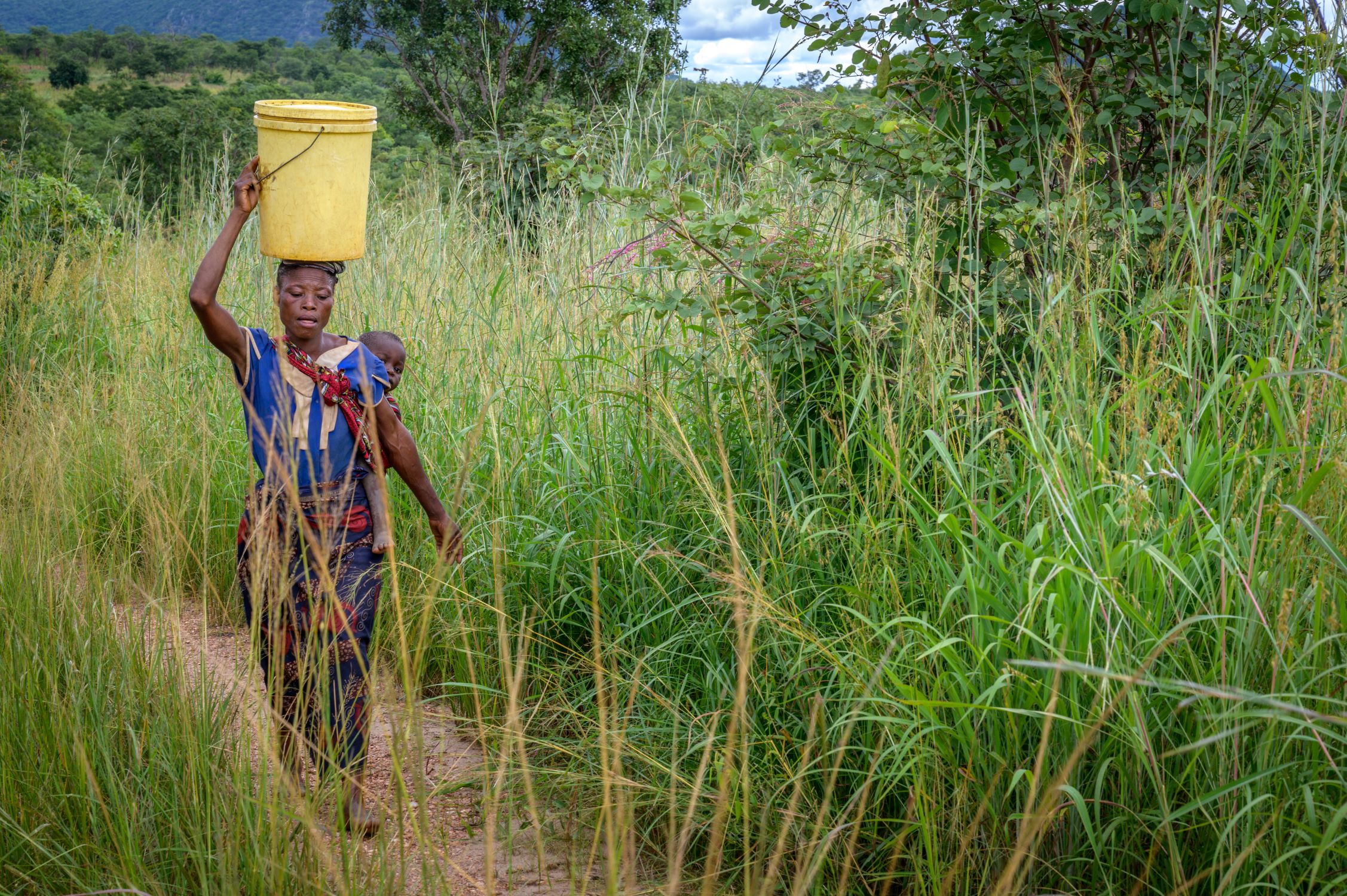 Zambian lady carrying water container on her head