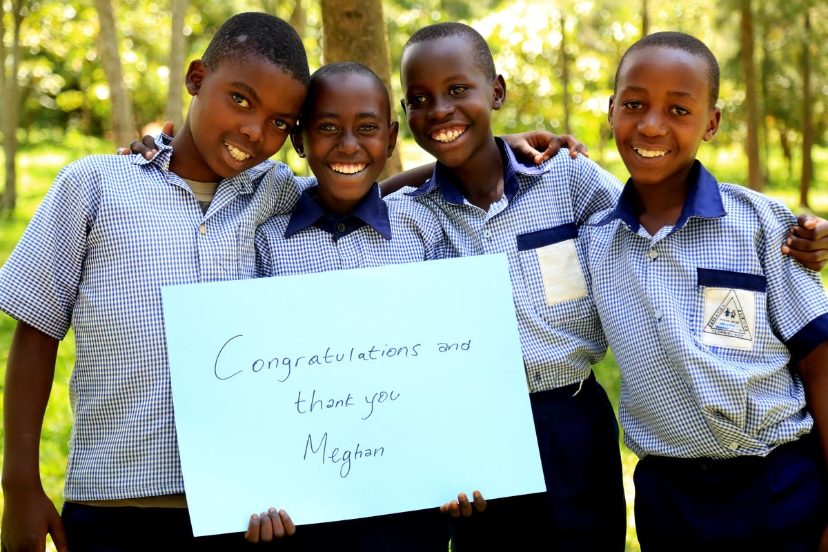 4 boys hold a sign saying "congratulations and thank you Meghan"