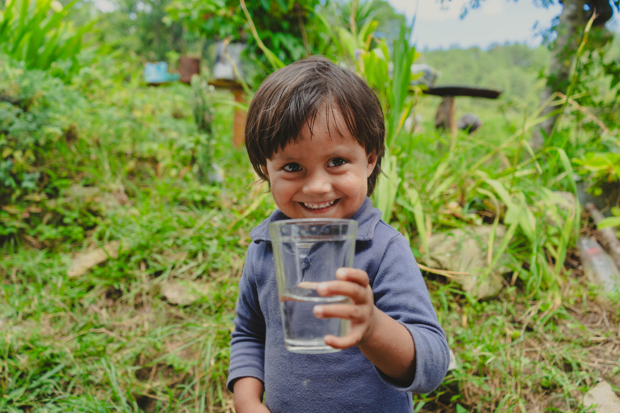 A girl in Uganda smiles while running clean water from a newly-installed tap