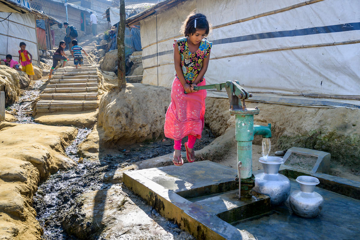 Young girl uses water pump in refugee camp in Bangladesh