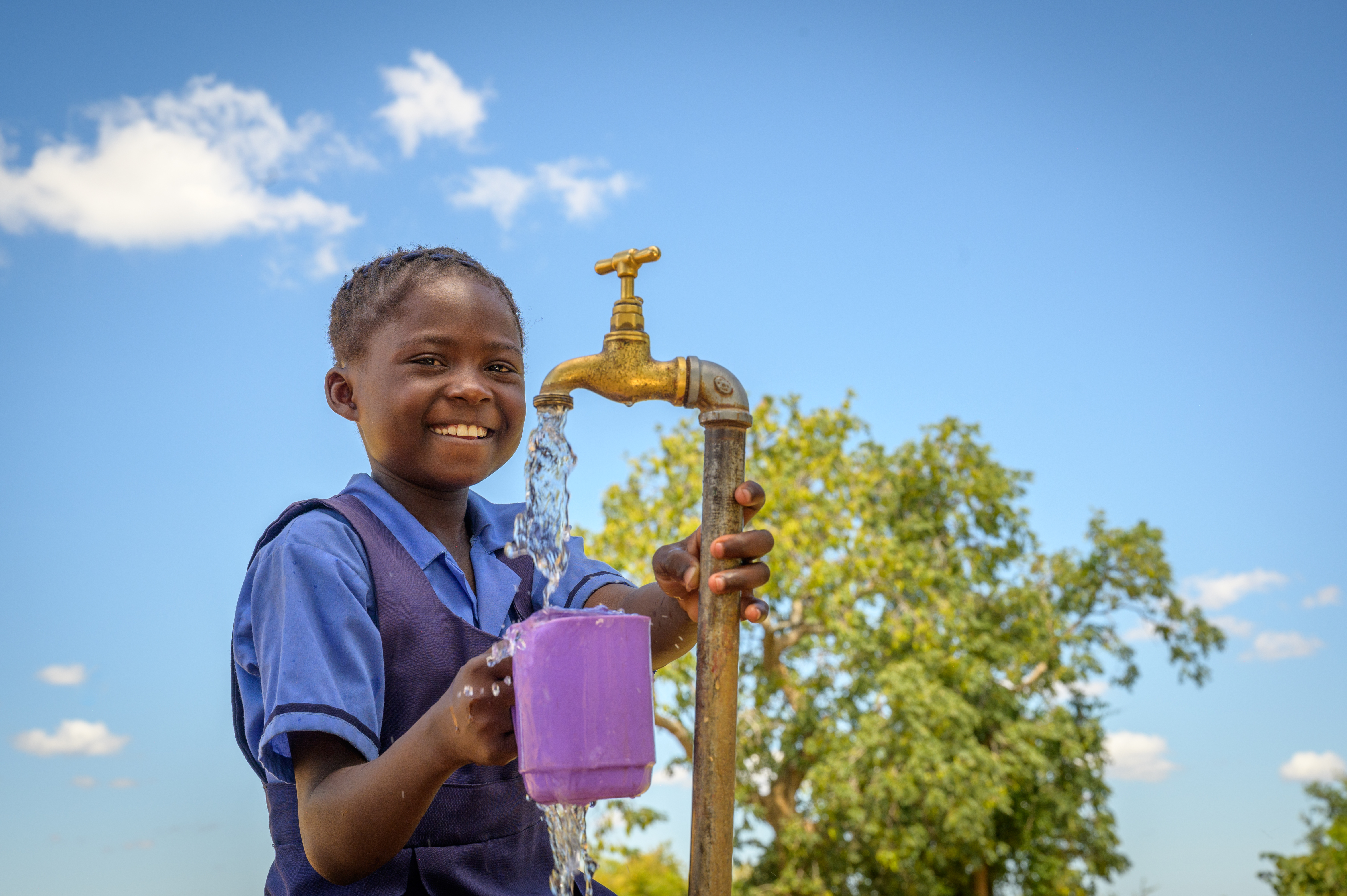 A young girl in Zambia collects clean water from a tap