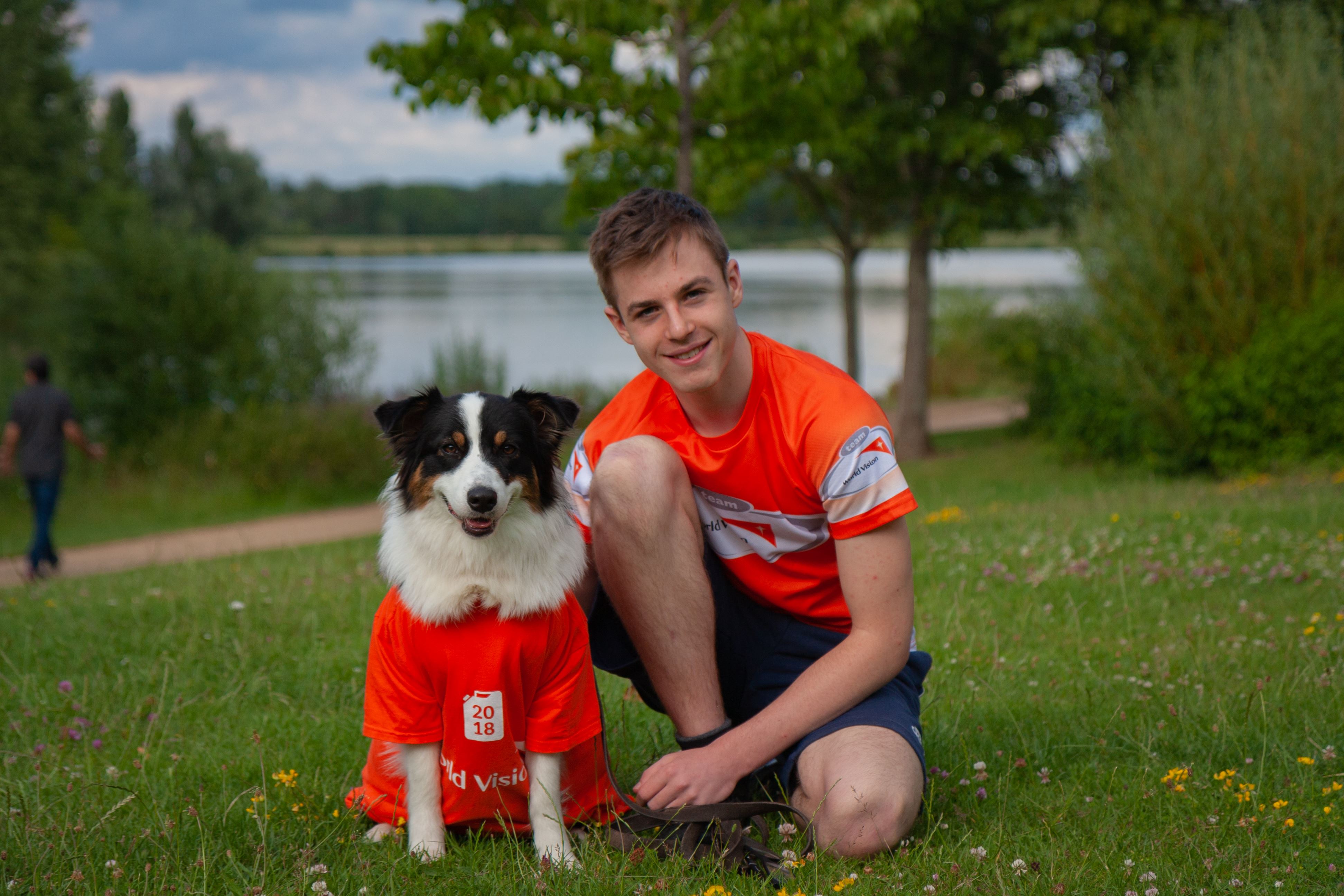 Teenage boy with dog outside both wearing orange World Vision t-shirts
