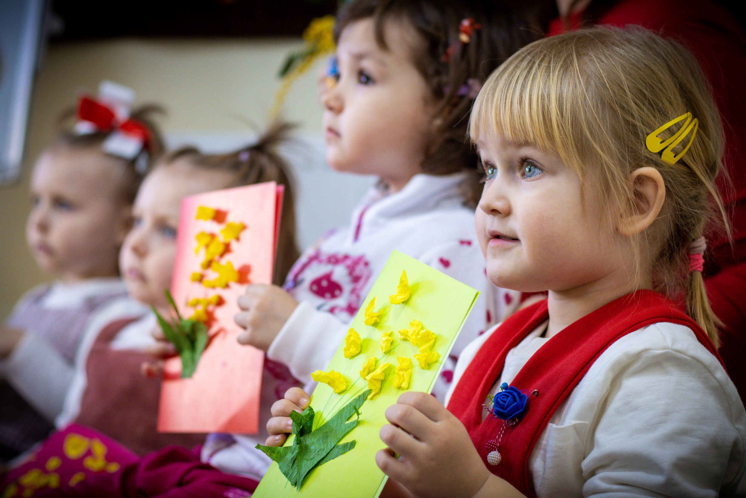Ukrainian girls holding up their colourful artwork at a Child-friendly Space in Moldova