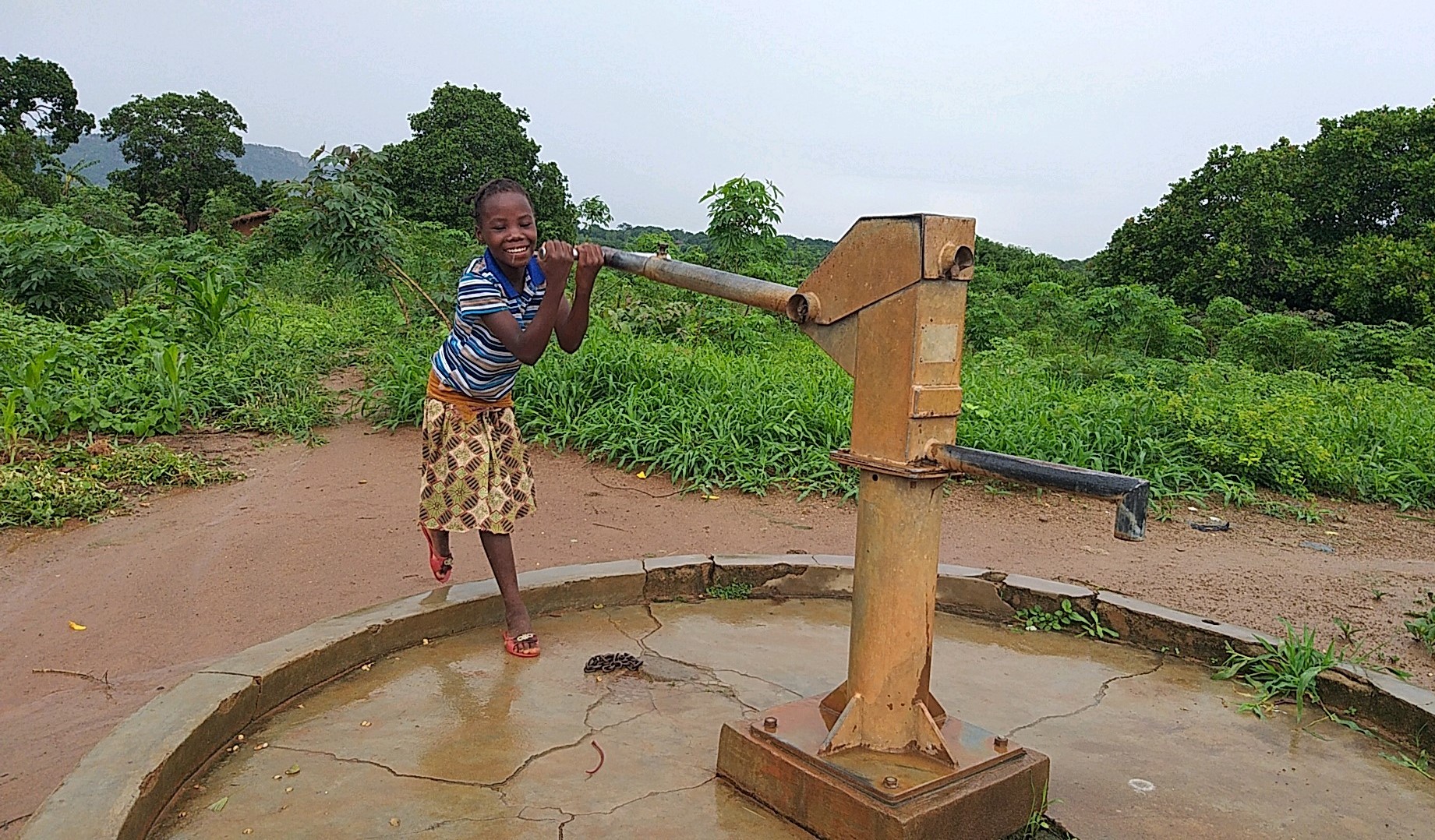 A child draws water from a pump in Pheone