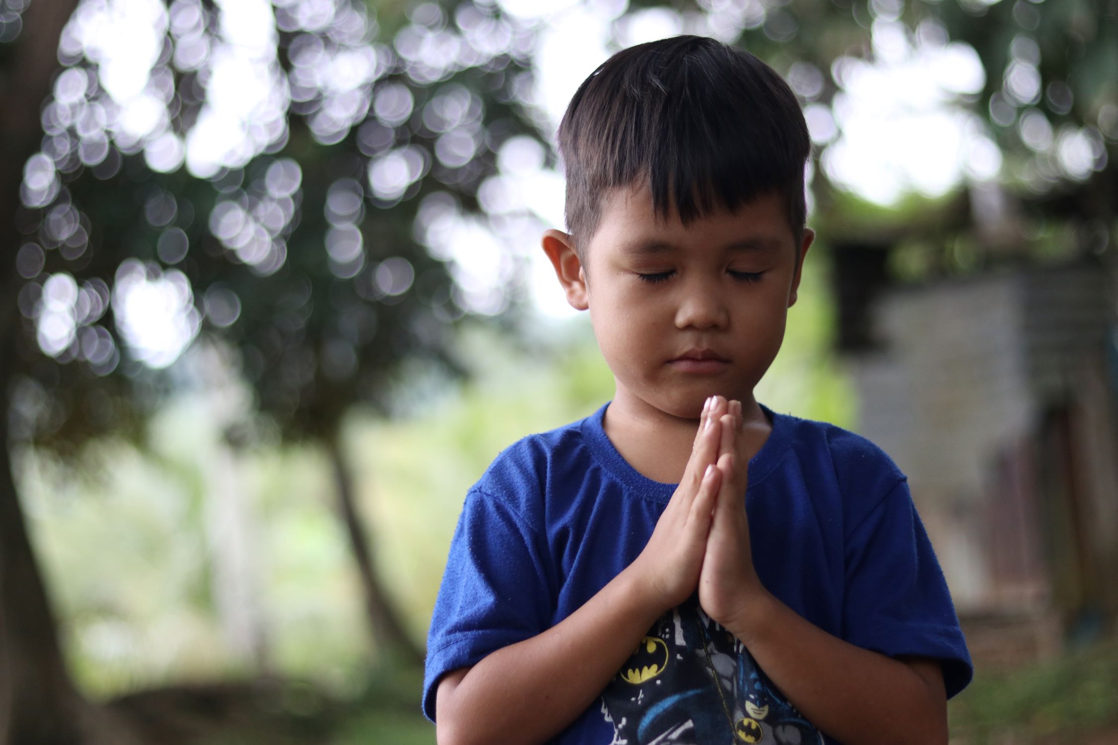 A boy in the Philippines with his hands held together in prayer